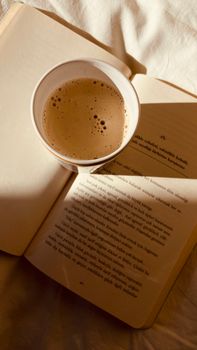 Warm sunlight on a cup of coffee and open book, perfect for a peaceful morning.