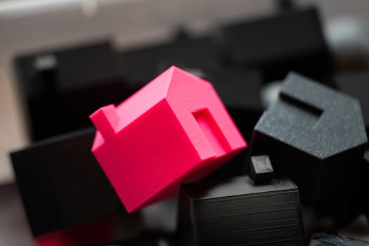 A bright pink house model stands out against a background of black blocks, symbolizing real estate uniqueness.
