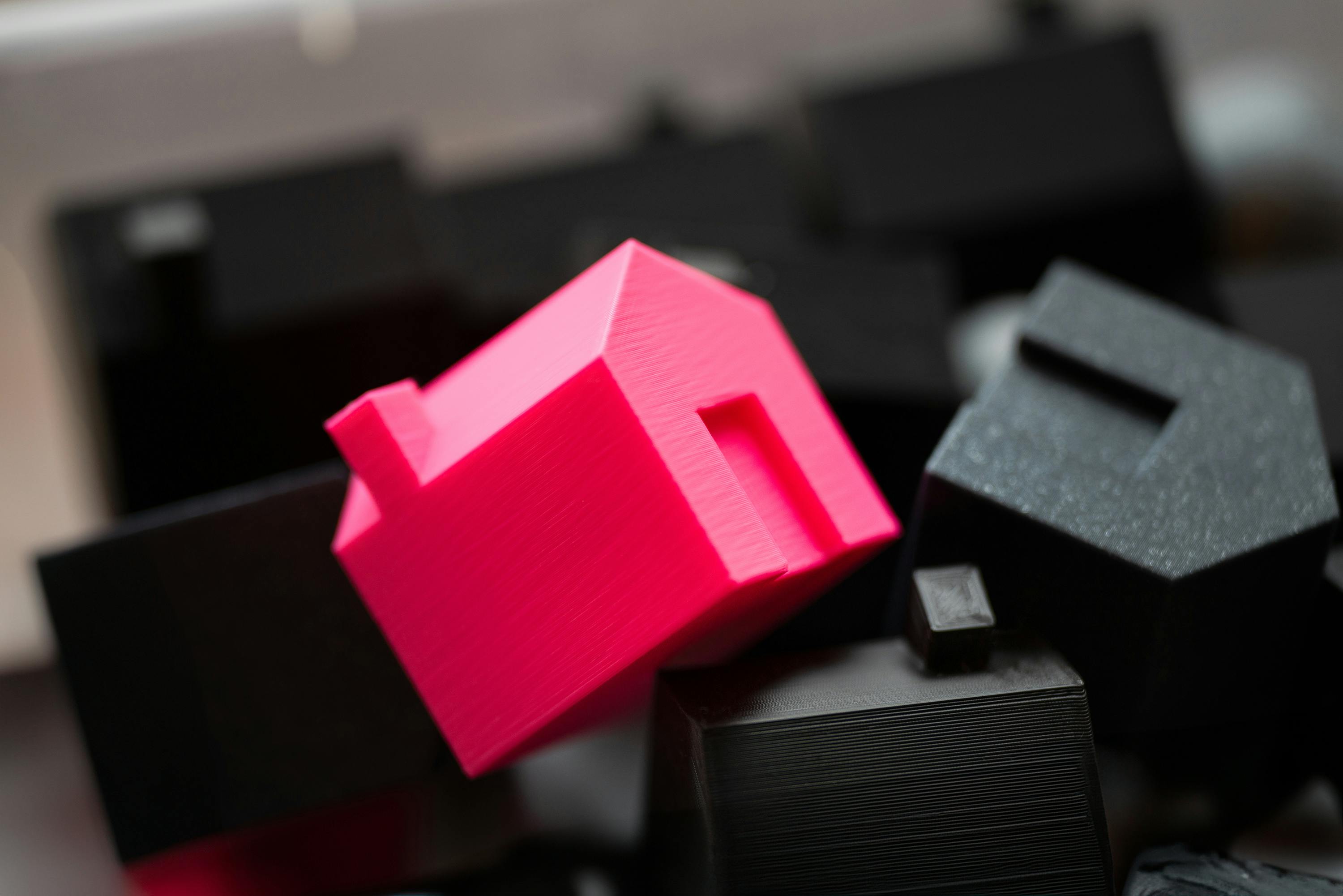 Miniature pink house among black houses – illustrating lucrative real estate