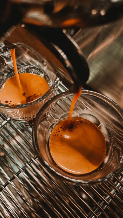 Free Rich espresso flowing into glass cups on a metallic espresso machine tray. Stock Photo