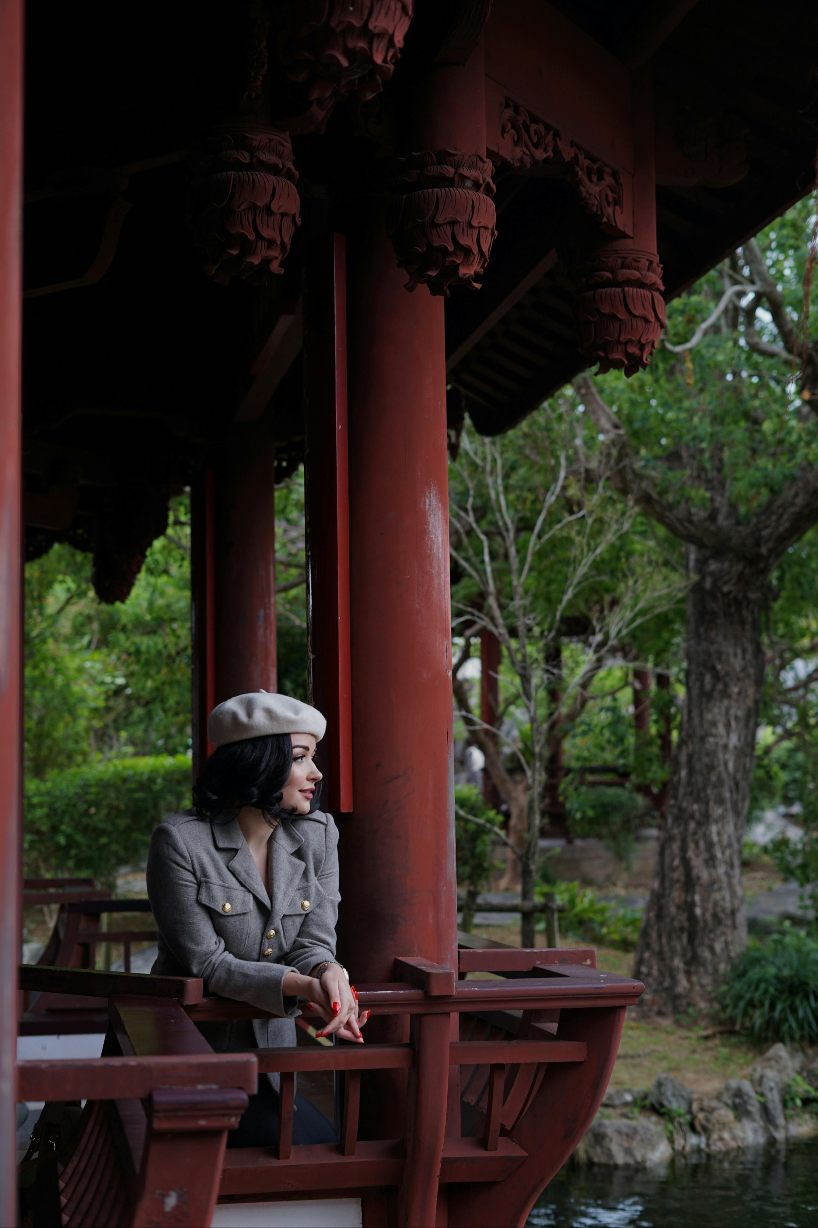 A woman enjoys a serene moment in a traditional Asian pavilion, surrounded by nature.