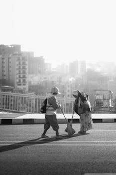 Two street sweepers at work on a quiet Ethiopian morning, with urban skyline backdrop.