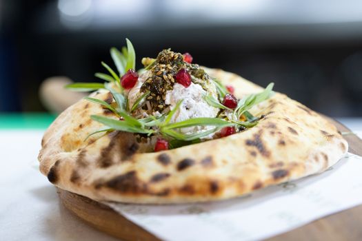 Delicious Middle Eastern flatbread with yogurt, herbs, and pomegranate seeds.