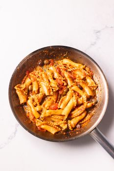 Cooked pasta with tomato sauce and olives in a frying pan, perfect for Italian cuisine lovers.