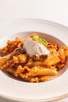 Appetizing Mafaldine pasta dish with ricotta cheese and olives in a restaurant setting.