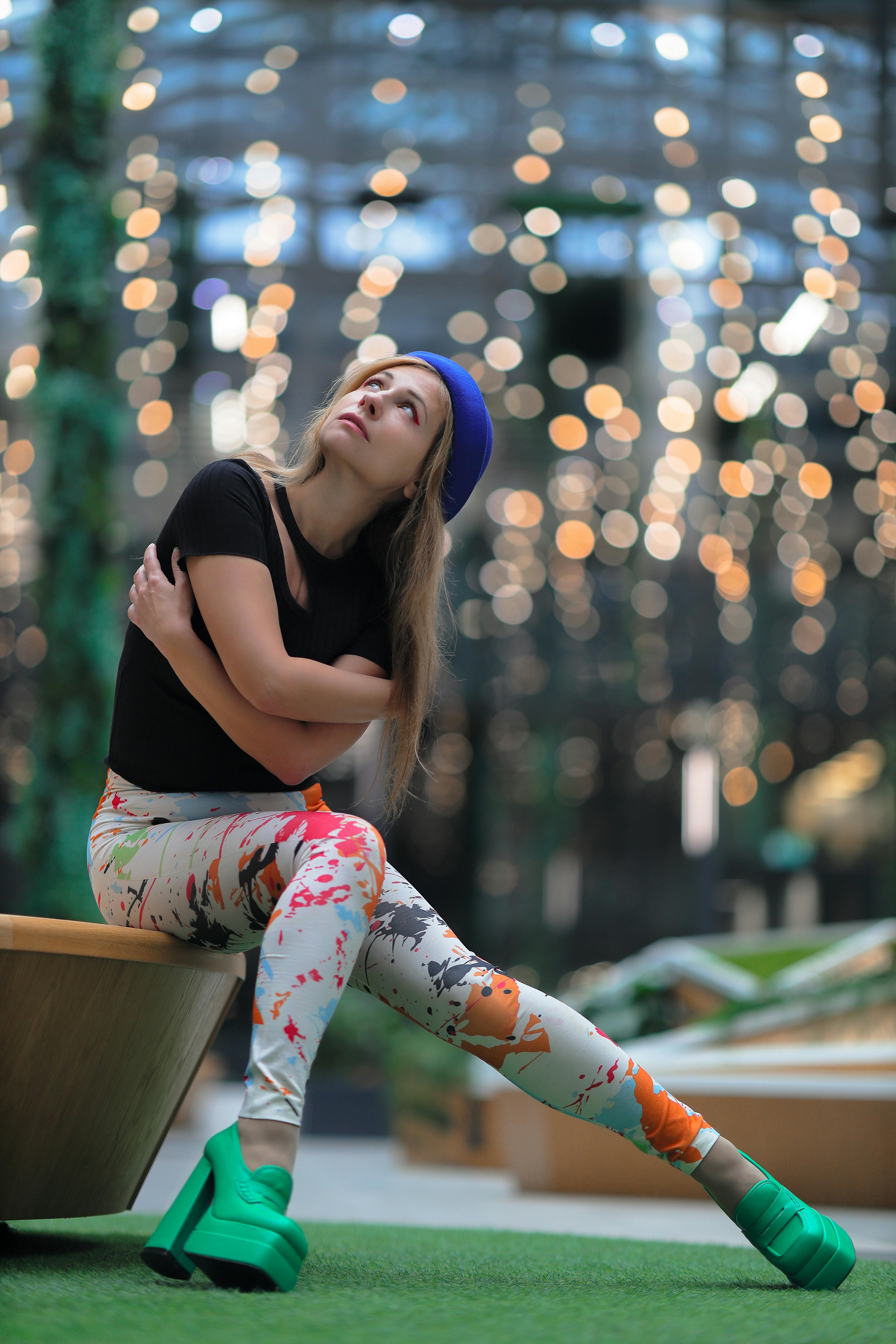 Femme en tenue colorée assise à l'intérieur avec un arrière-plan à effet de lumière bokeh. - illustration