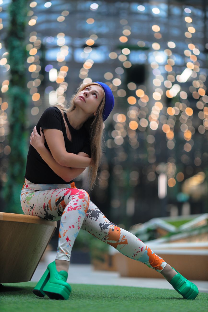 Femme en tenue colorée assise à l'intérieur avec un arrière-plan à effet de lumière bokeh. - illustration