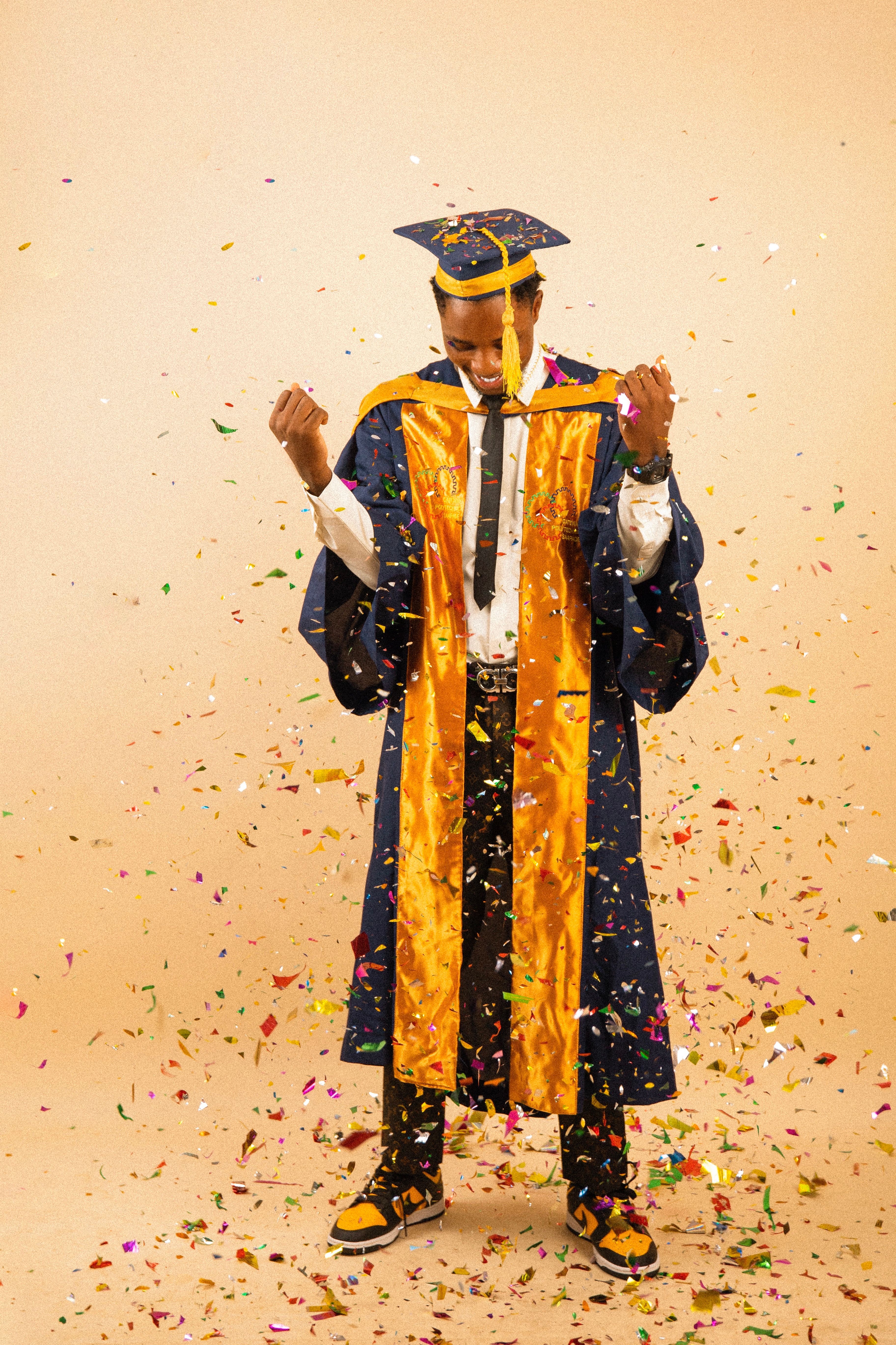 Graduate celebrating with confetti in cap and gown