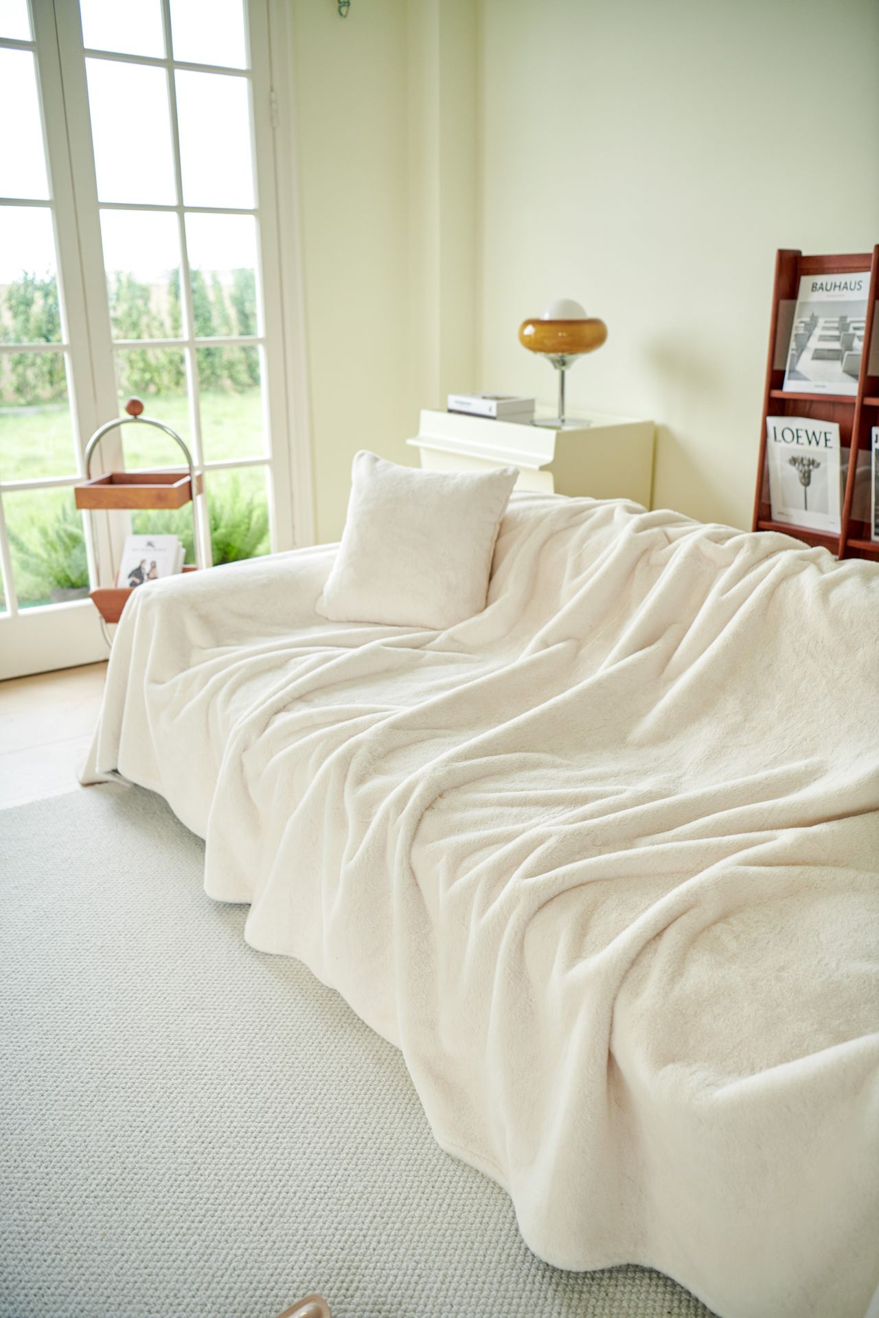 Beige sofa layered with cushions and a throw blanket