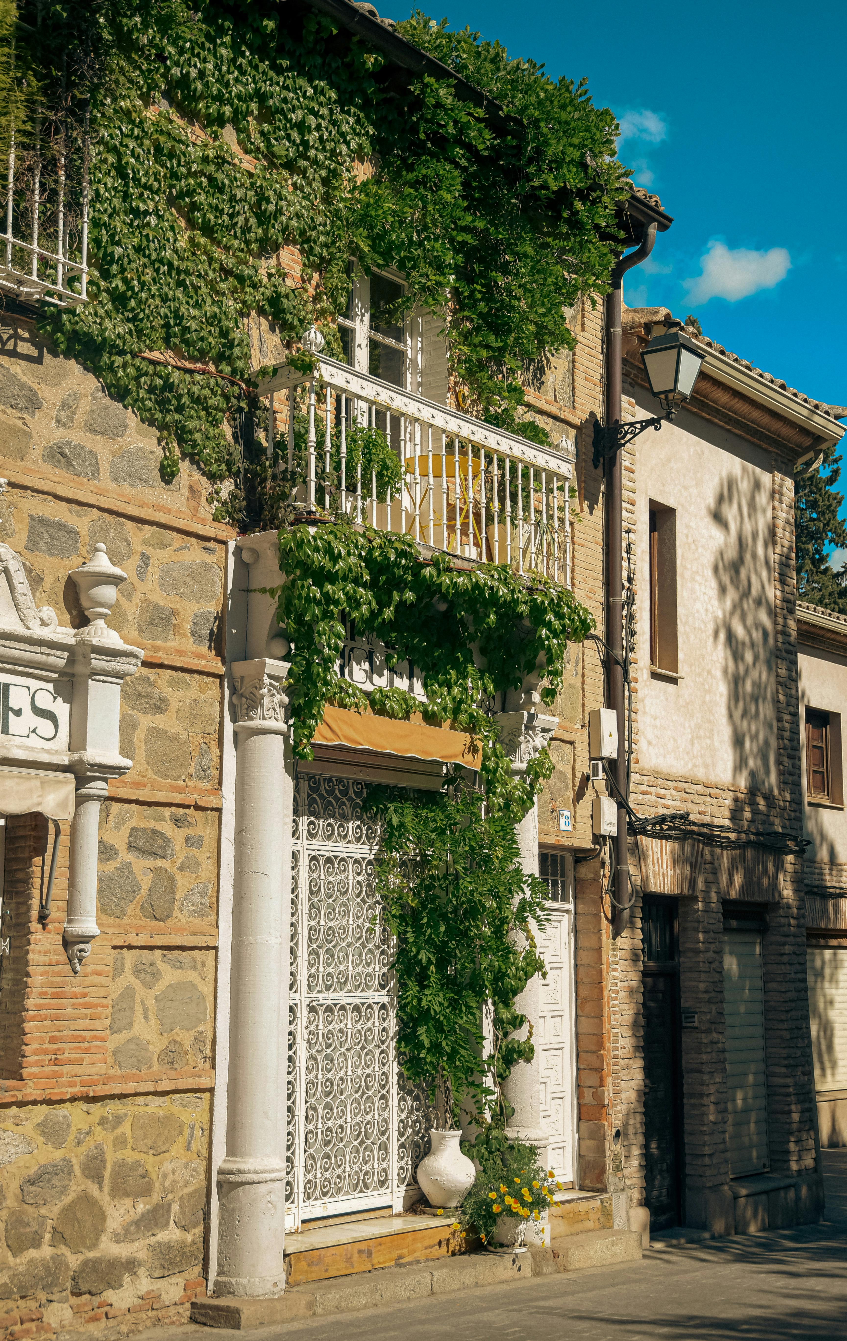 Charming view of a vine-covered balcony on a stone building in Toledo, Spain.