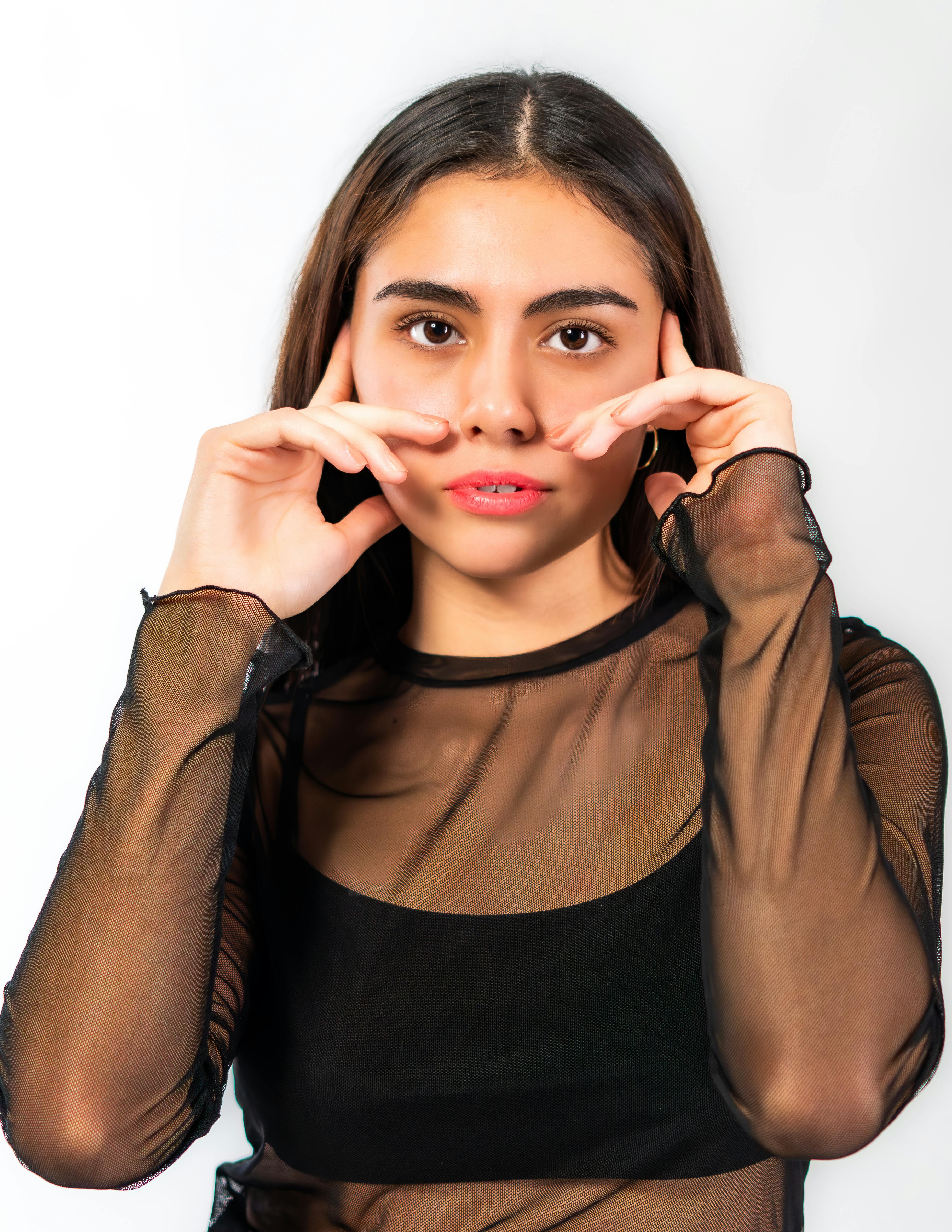 Gratuit Portrait d'une femme dans un haut noir transparent avec une pose créative, mettant en valeur l'élégance et l'autonomisation. Photos