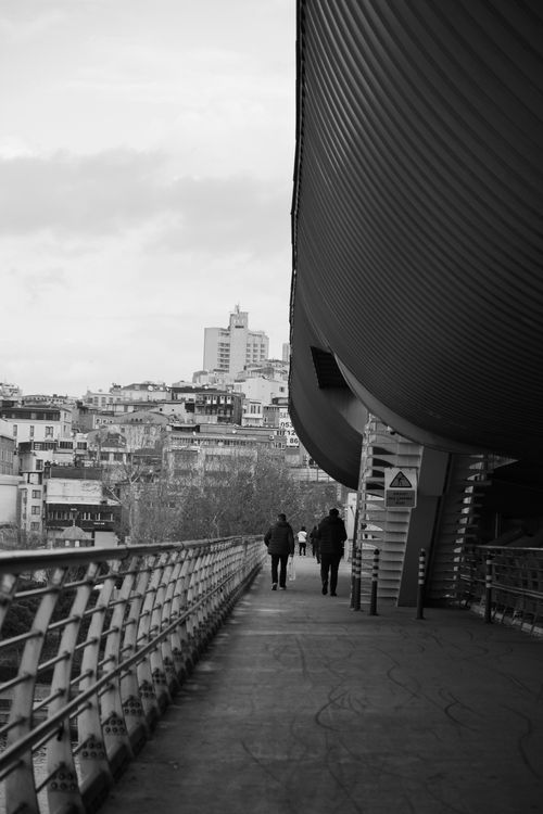 Free Two people walking on a modern bridge with cityscape views in Istanbul. Stock Photo