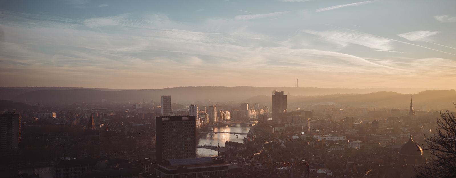 Scenic view of Liège with warm sunset hues reflecting over the Meuse River.