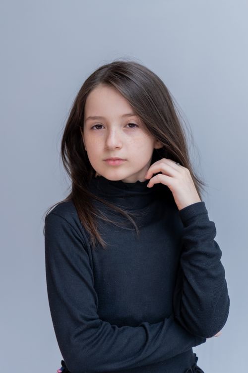 Free A young girl poses confidently in a black turtleneck against a neutral background. Stock Photo