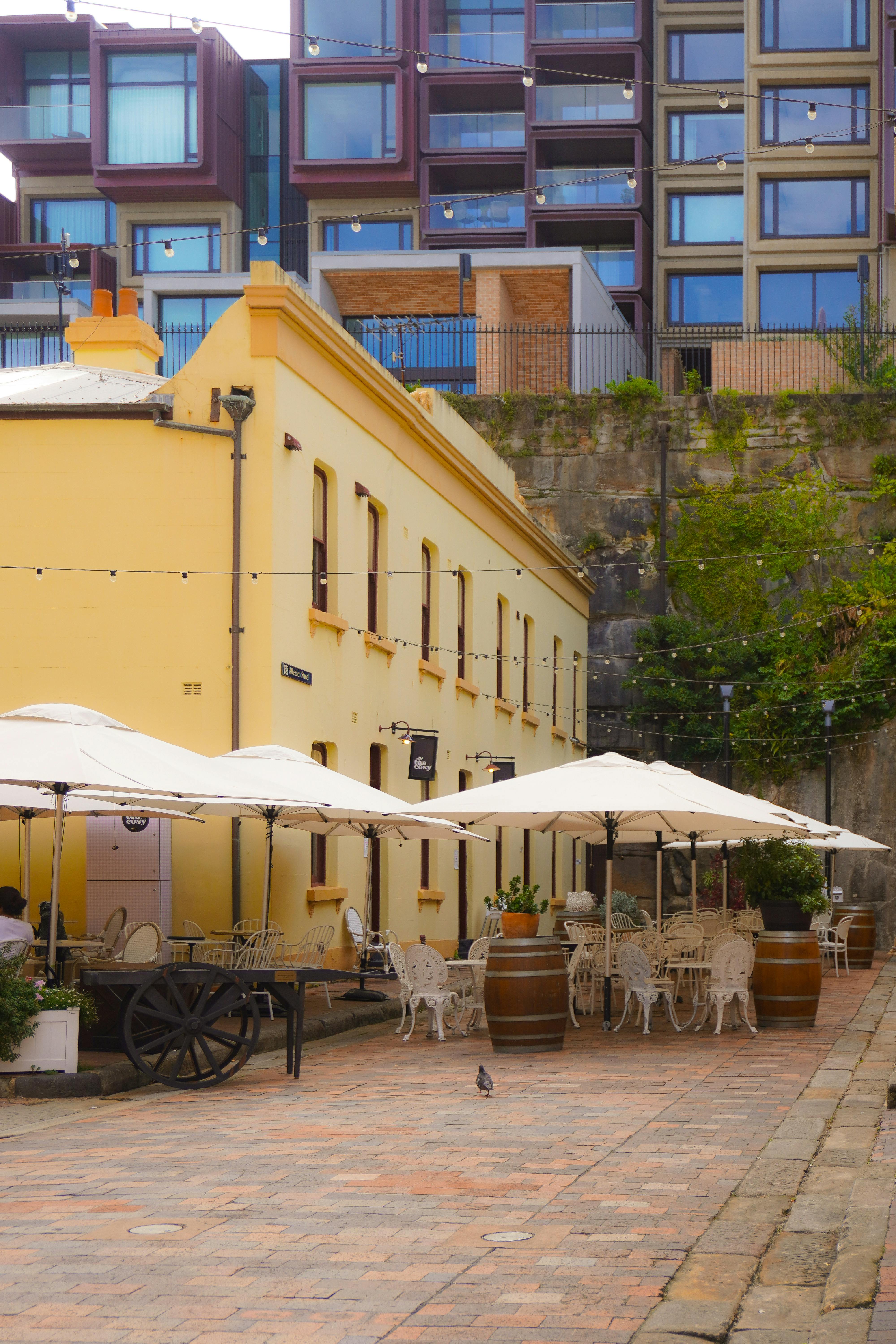 Gratuit Cafenea în aer liber cu farmec de epocă, situată într-o zonă urbană istorică sub șiruri de lumini. Fotografie de stoc