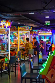 Colorful arcade with people enjoying games. Bright neon lights.