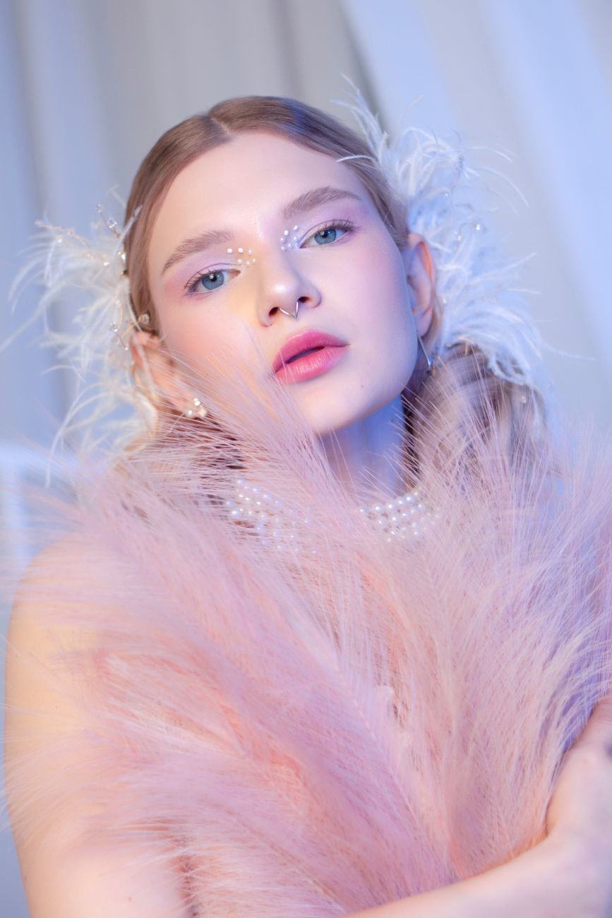 Elegant portrait of a woman adorned with pink feathers and pearls, showcasing dreamy beauty.