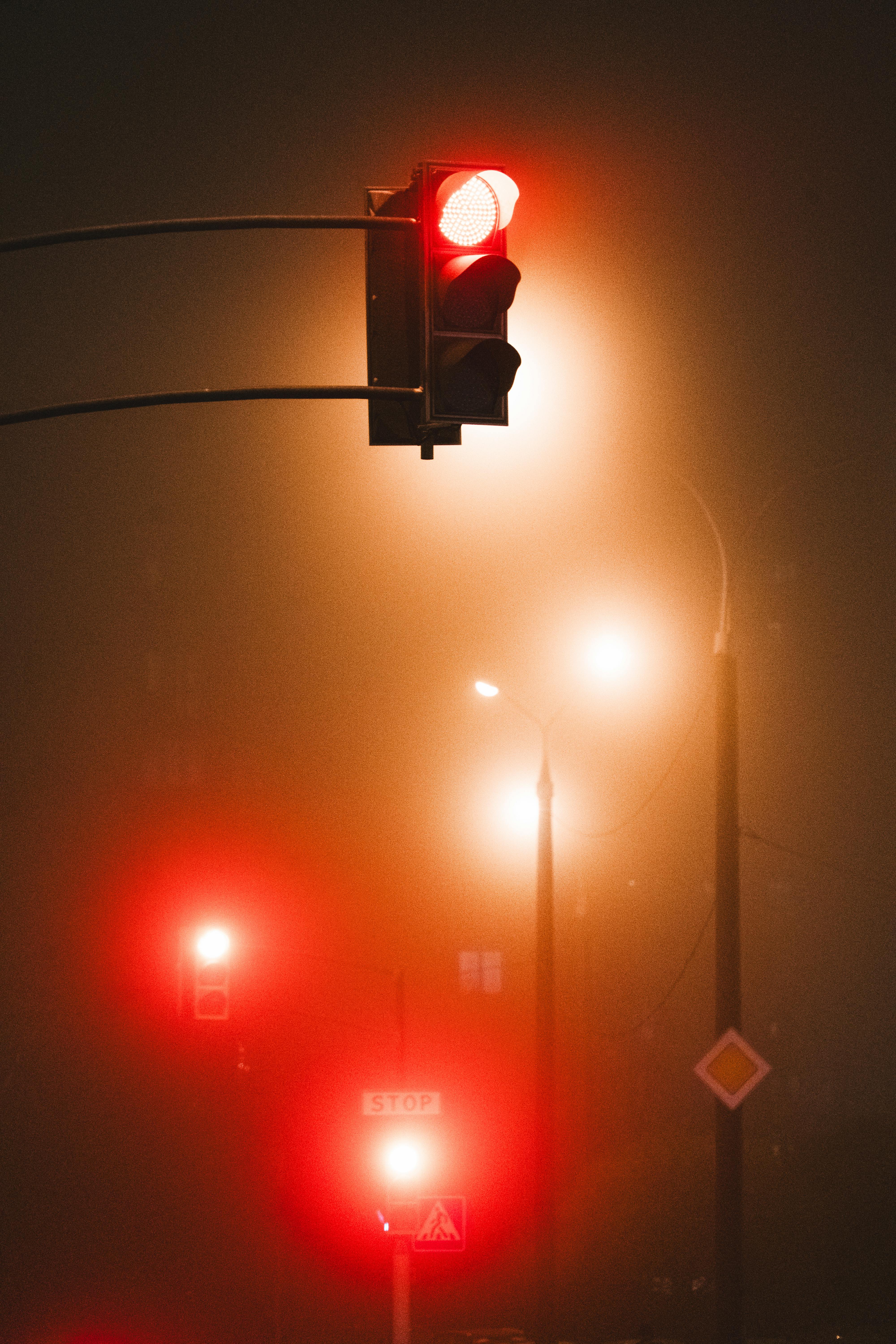 Eerie city nightscape featuring glowing red traffic lights in the mist.