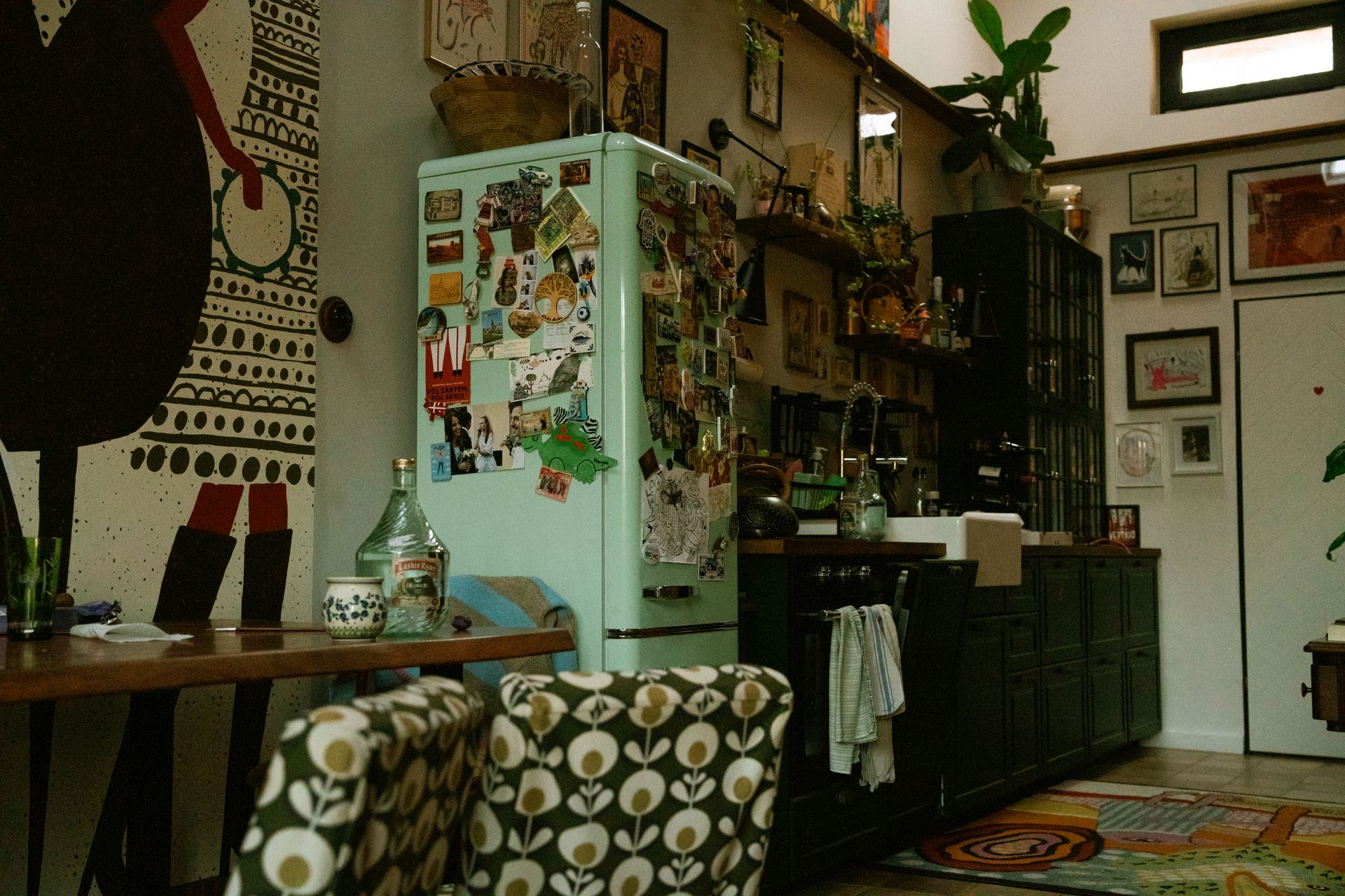 Stylish kitchen interior featuring retro fridge, vibrant art, and cozy, eclectic design elements.
