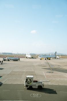 A busy airport with airplanes on the tarmac, under a clear sky.