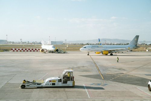 Free Vueling Airlines plane taxiing on an airport runway with clear sky. Stock Photo