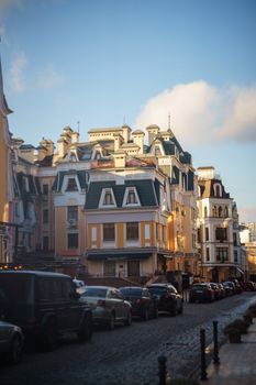 Beautiful European street with historic architecture and parked cars under a bright blue sky.