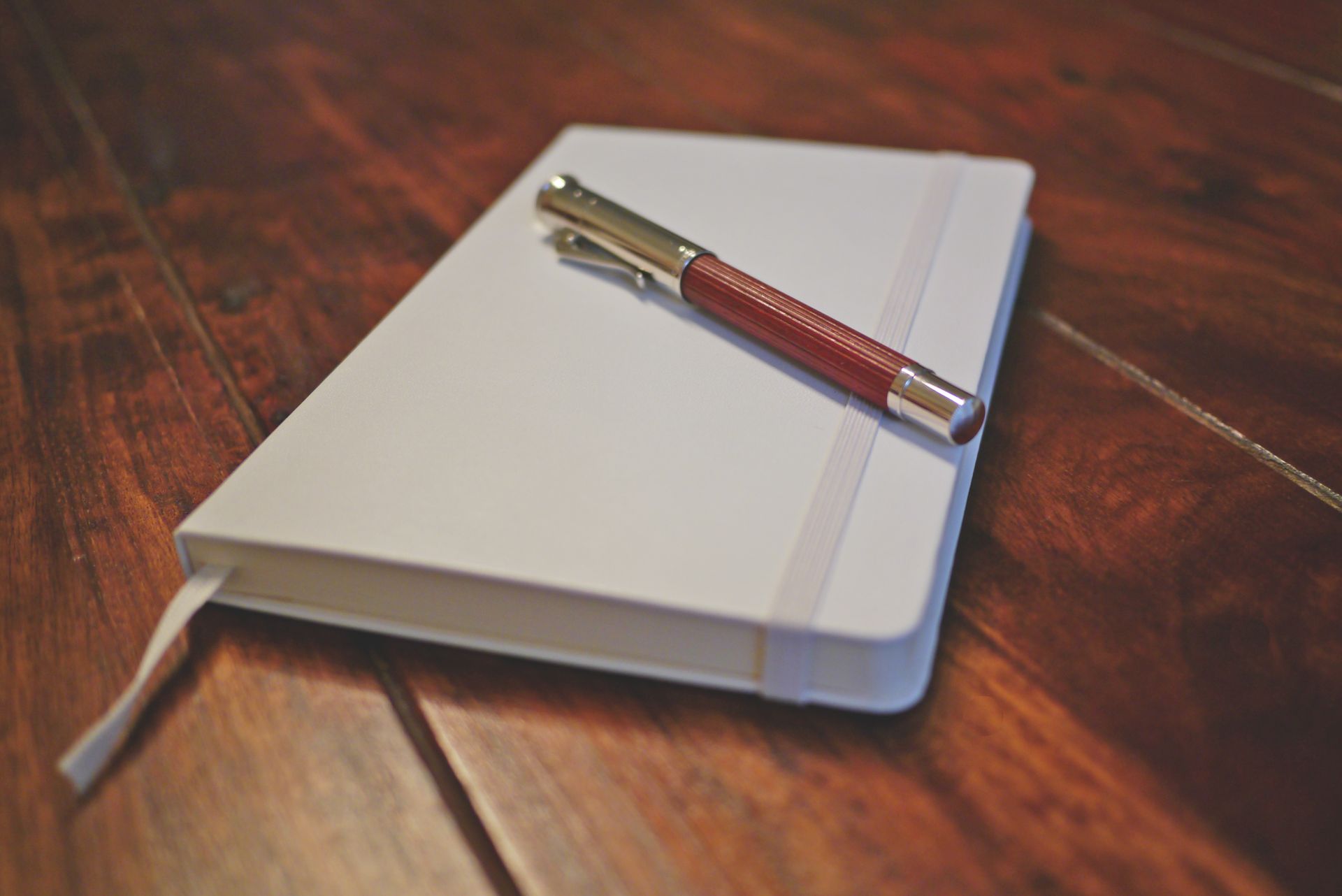 A minimalist flat lay of a premium notebook and pen on a wooden desk