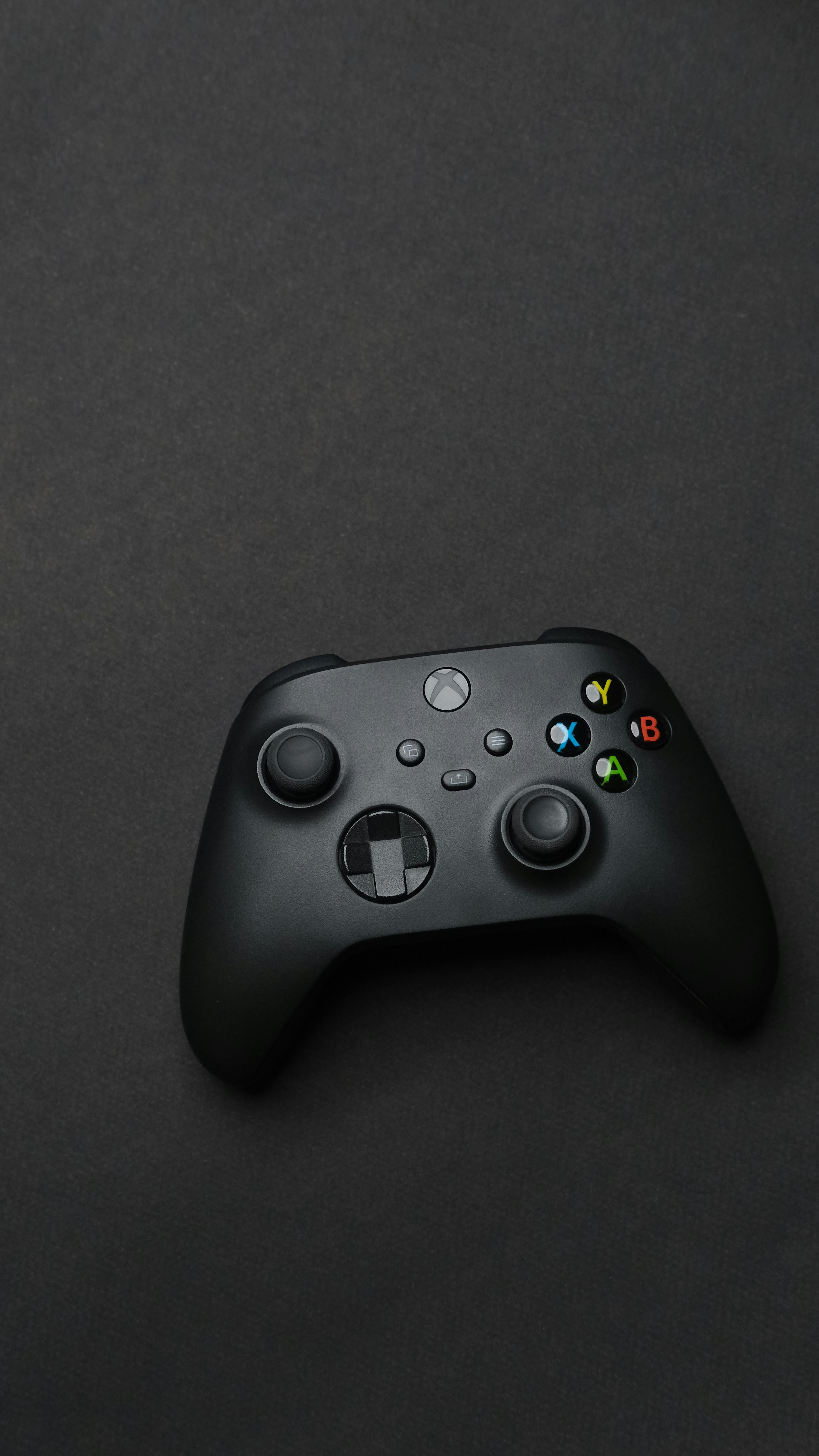 Black gaming controller on a dark backdrop, perfect for tech and gaming themes.