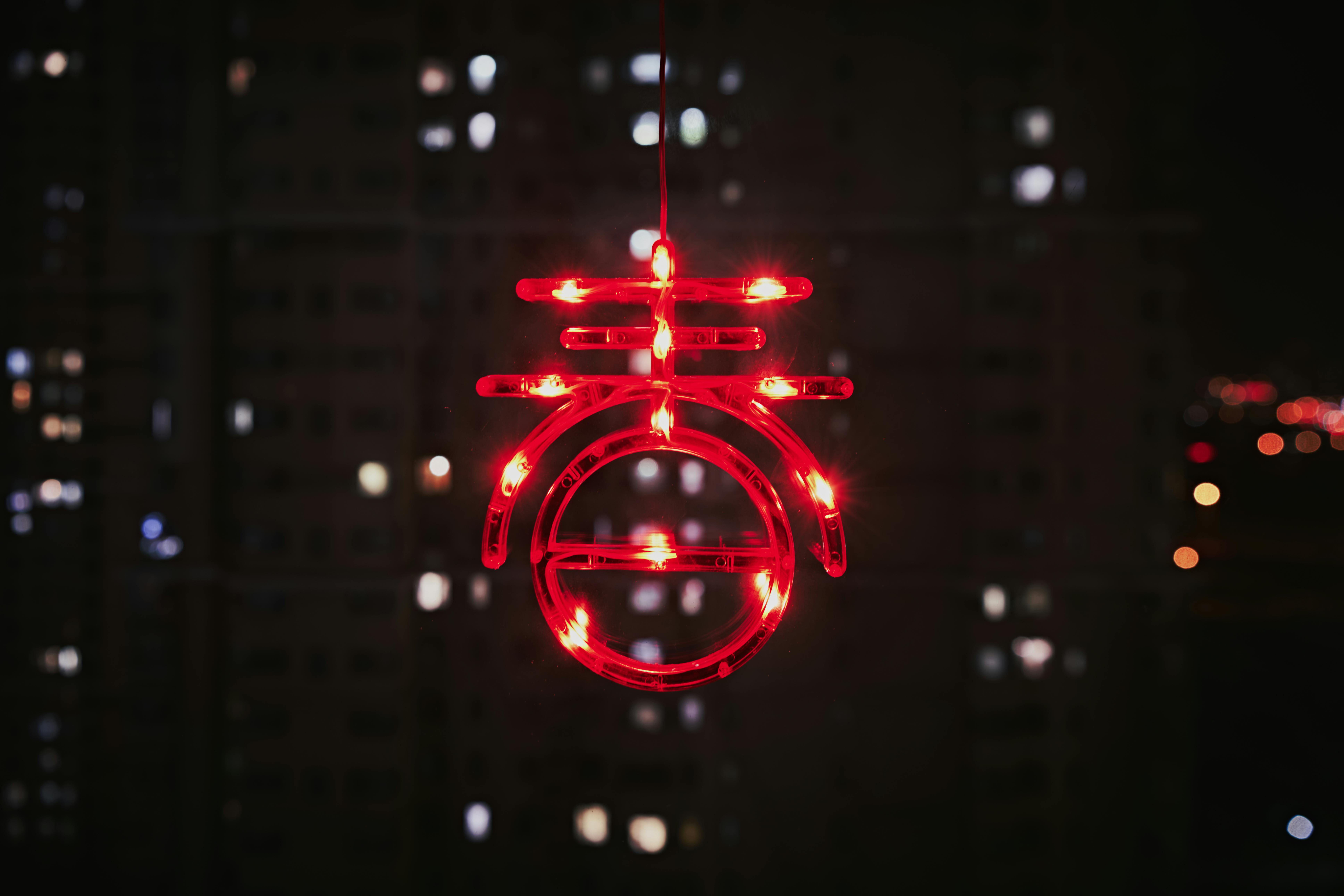 Kostenlos Ein leuchtend rotes Neonsymbol, das die Nacht vor einer Stadtkulisse erhellt Stock-Foto