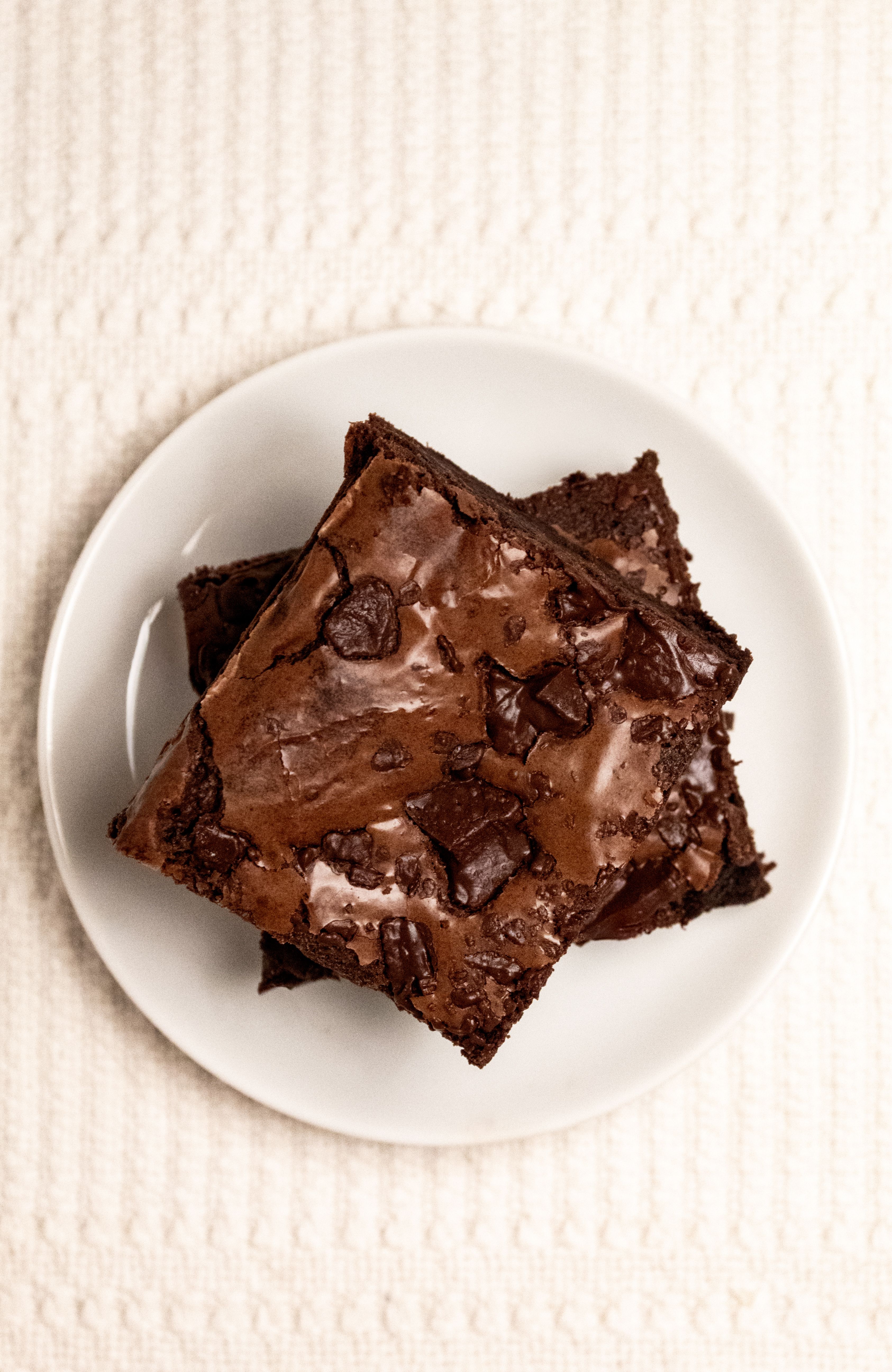 Top view of freshly baked chocolate brownies on a white plate, perfect for dessert lovers.