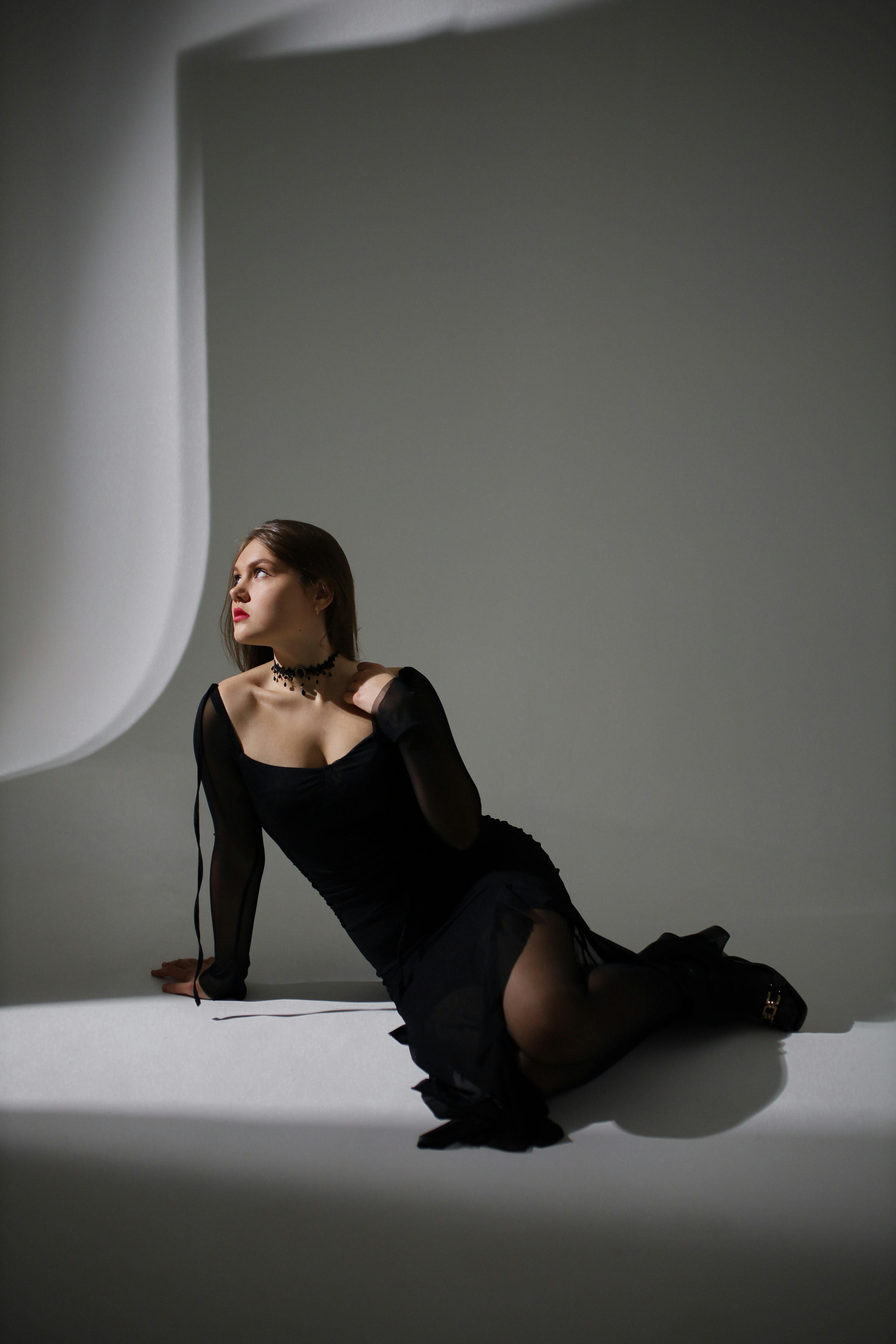 Artistic portrait of a woman in a black dress, emphasizing elegance and mood in a studio setting.