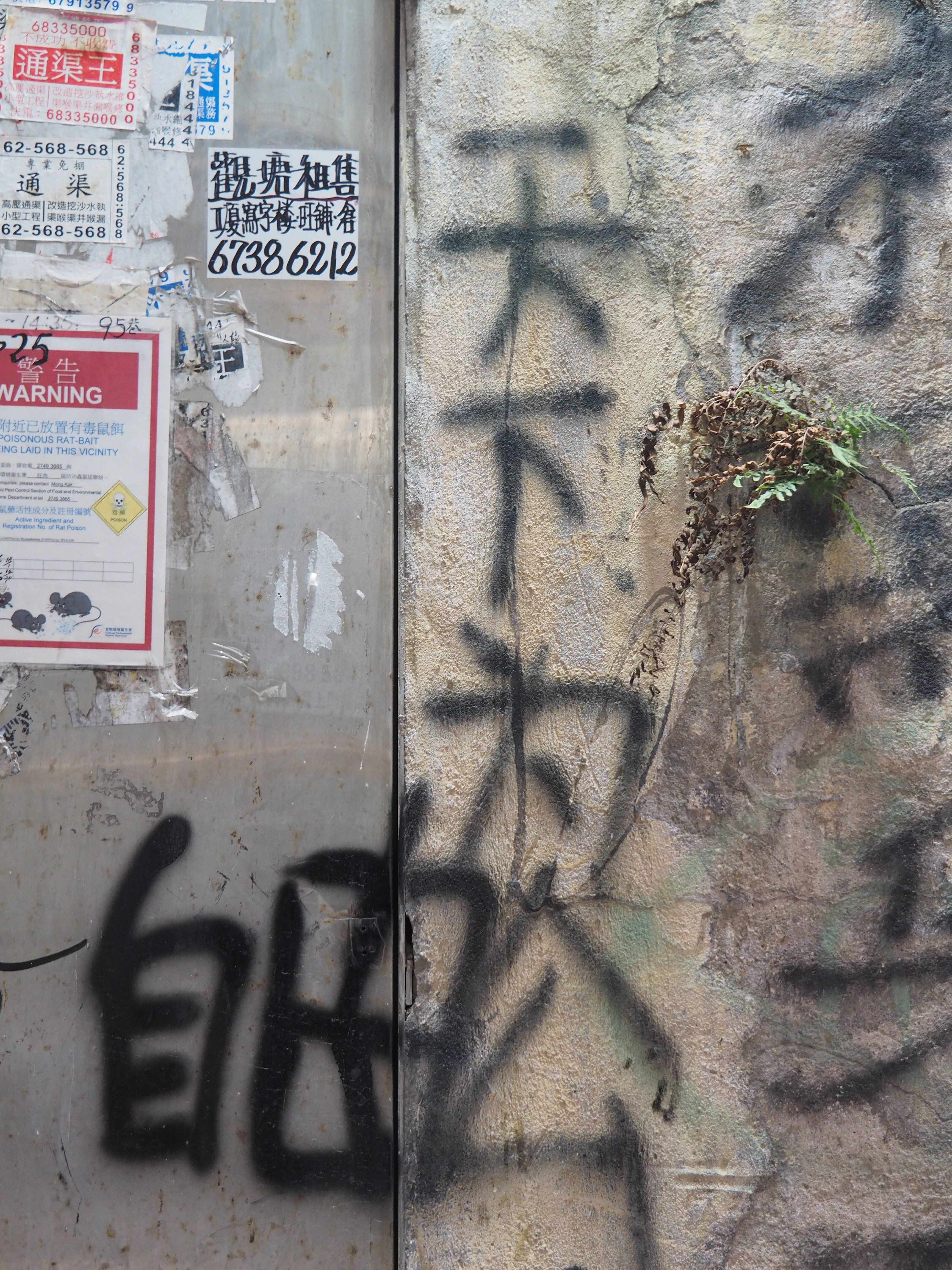 Graffiti art with faded signs on a rustic wall in Hong Kong, portraying urban culture.
