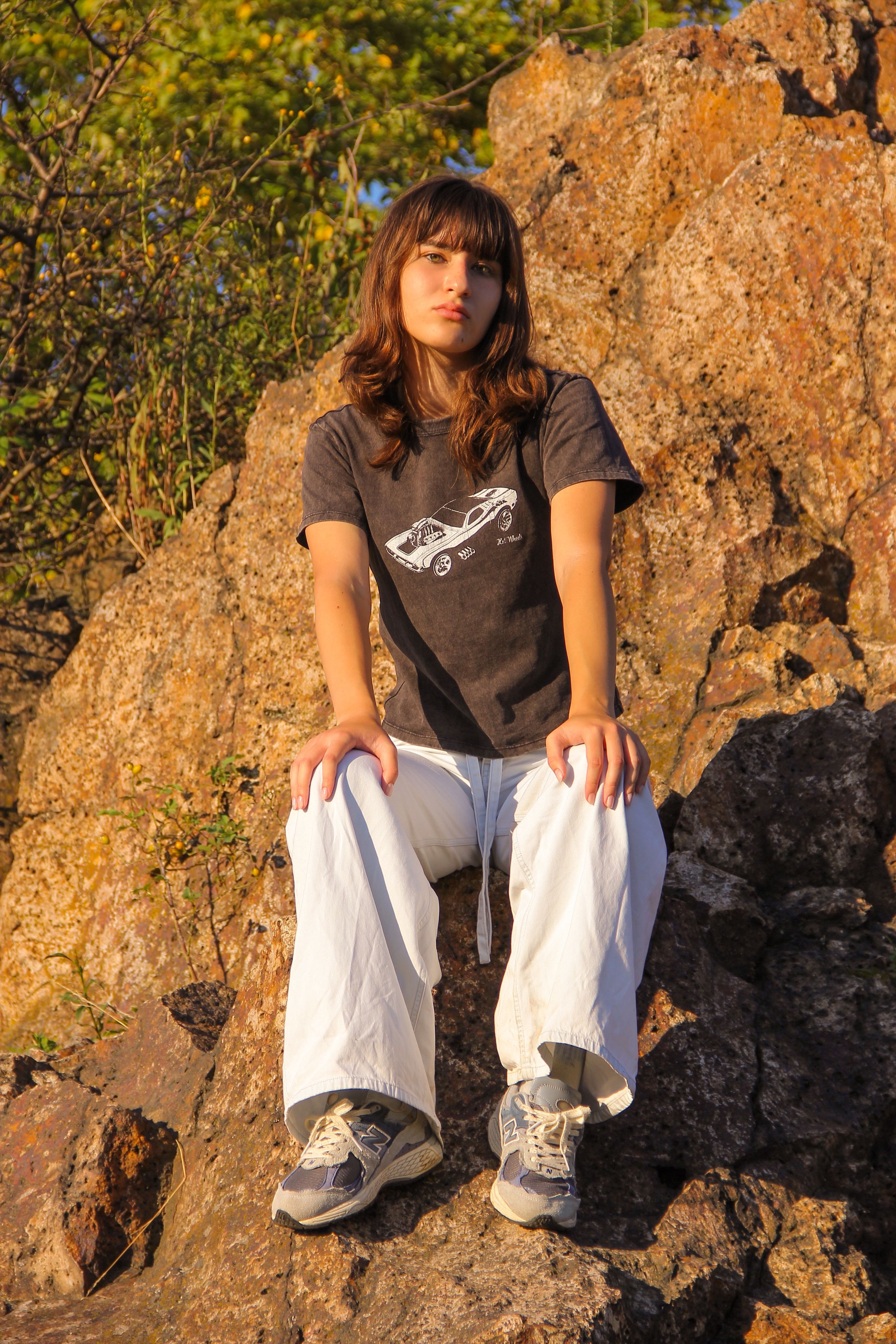 Young Woman Sitting on Rocky Terrain in Sunlight · Free Stock Photo