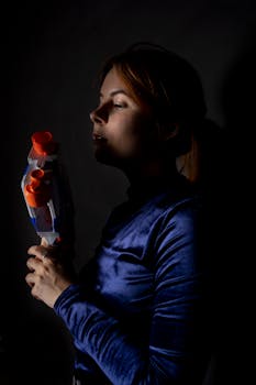 黑暗背景下，一个女人手持玩具枪的肖像显得喜怒无常