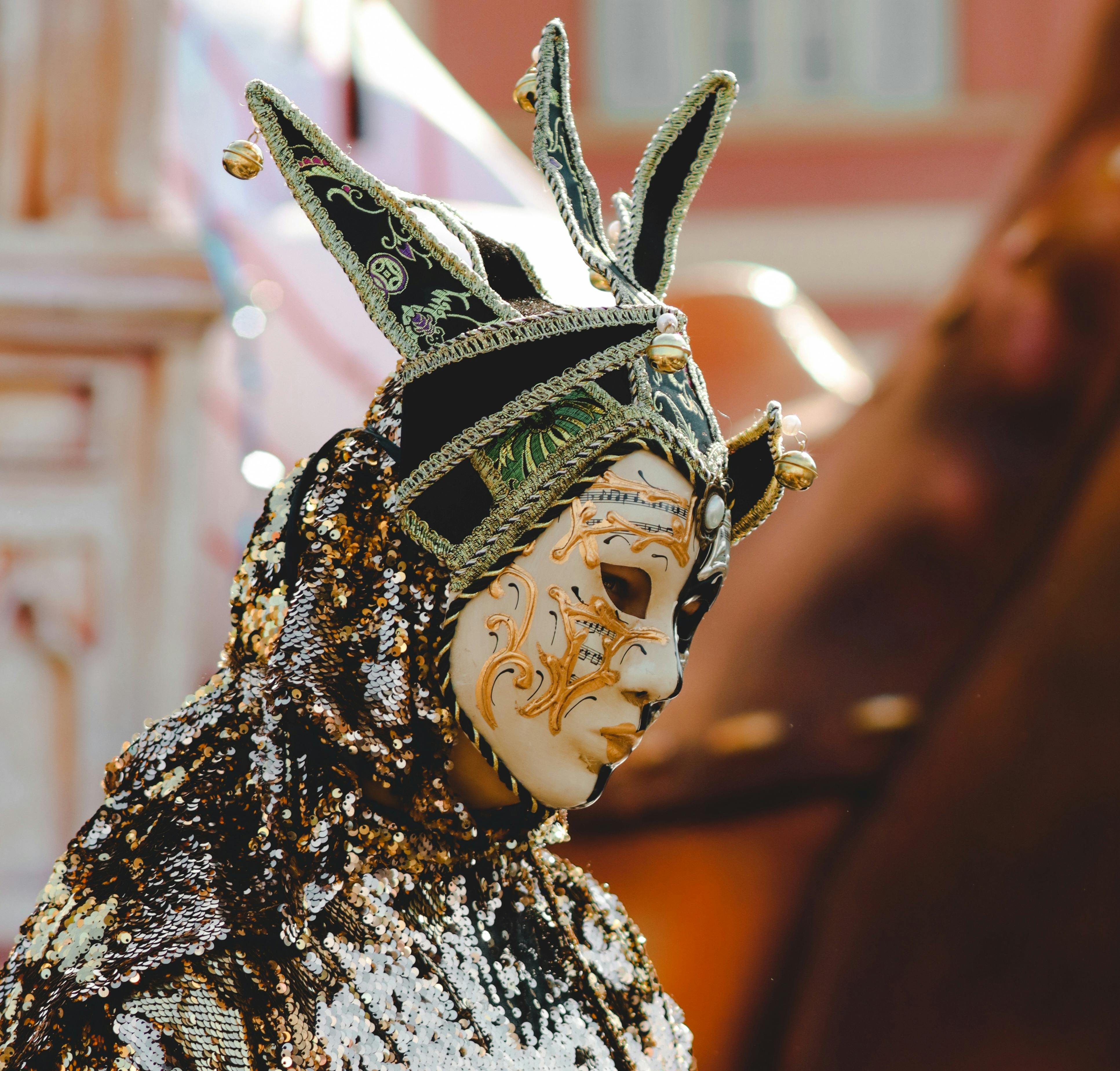 Colorful jester-style mask with intricate designs worn at a festive Venice carnival.