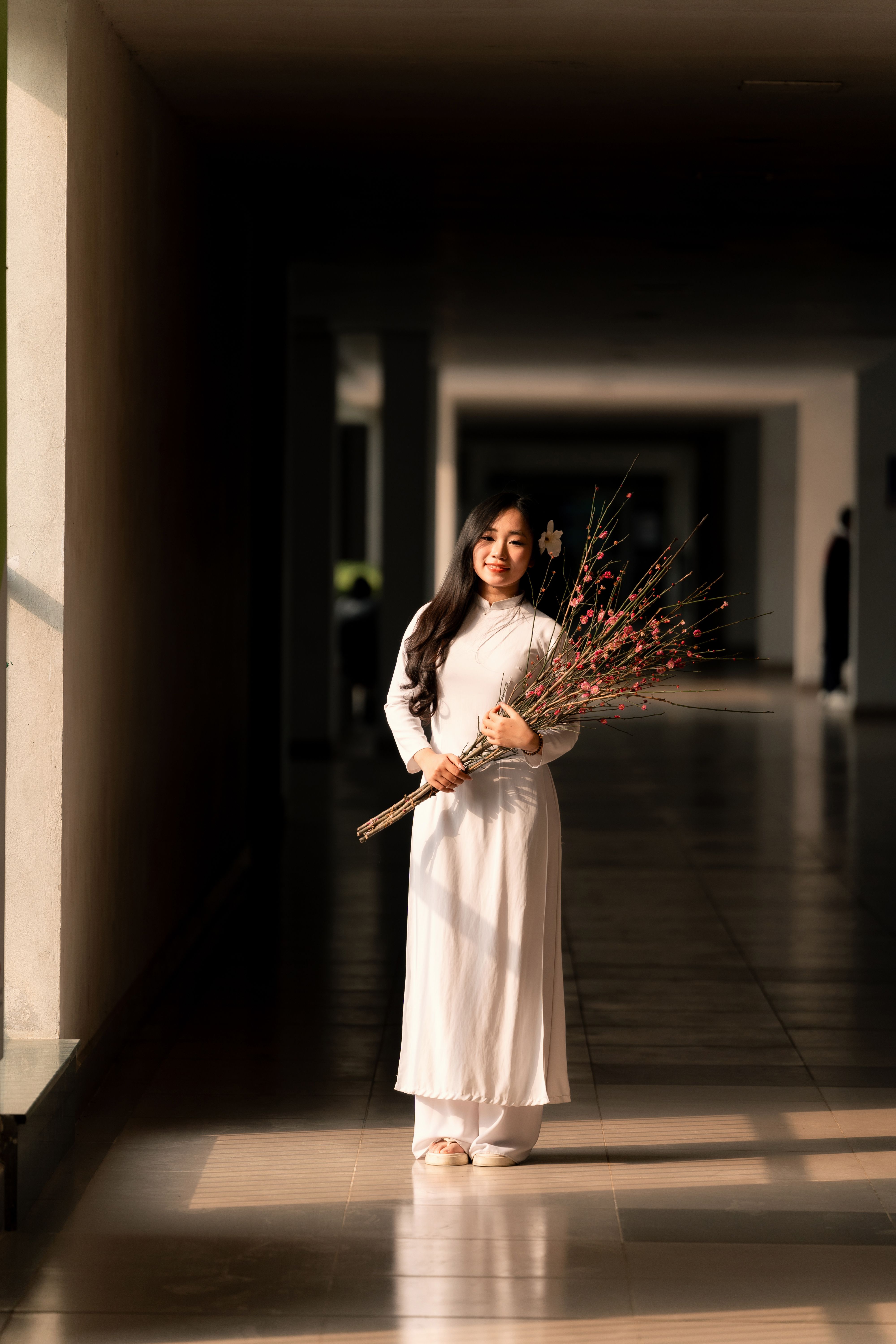 Elegant portrait of a woman in traditional Vietnamese ao dai holding peach blossoms