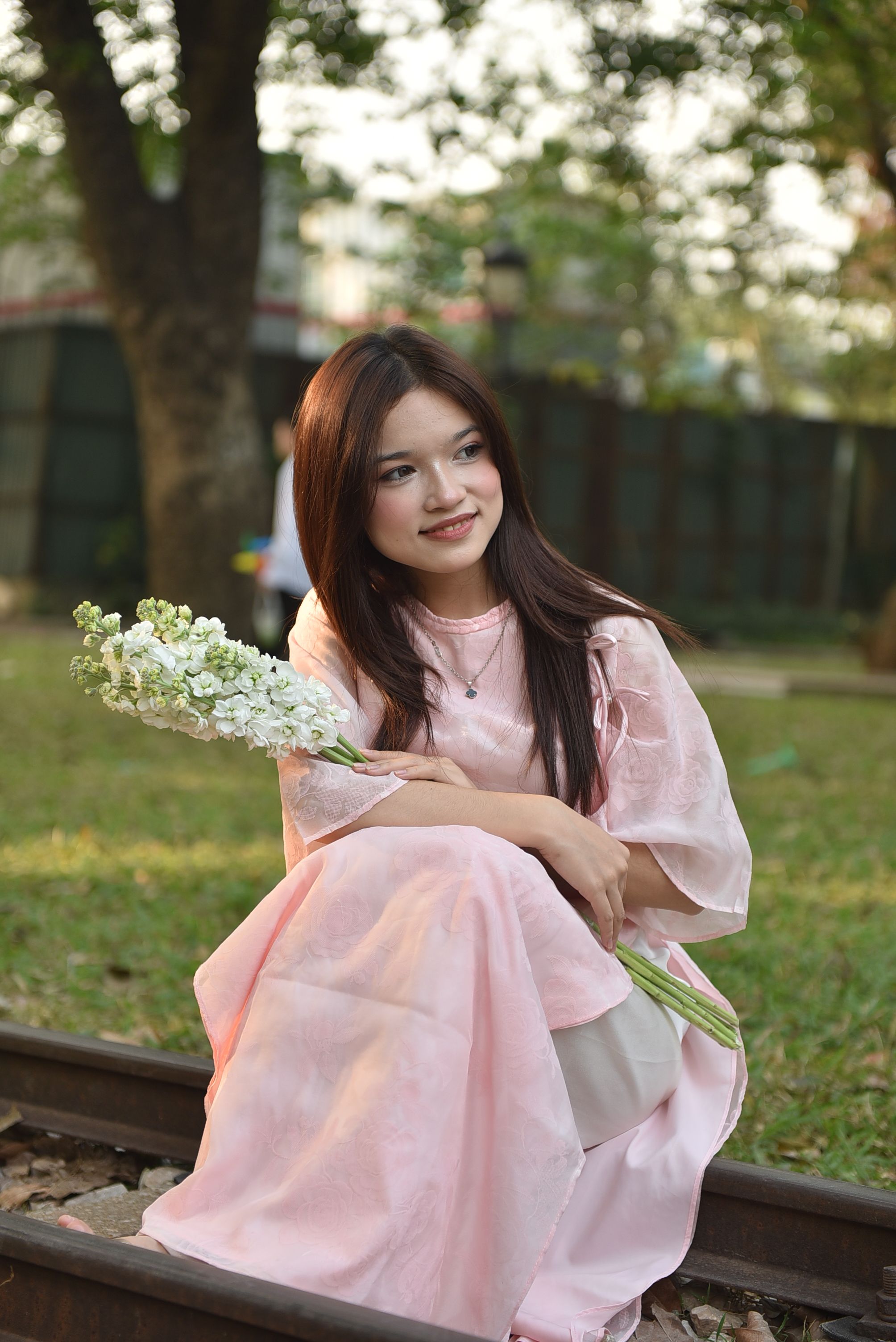 Young Woman in Pink Dress Holding Flowers Outdoors · Free Stock Photo