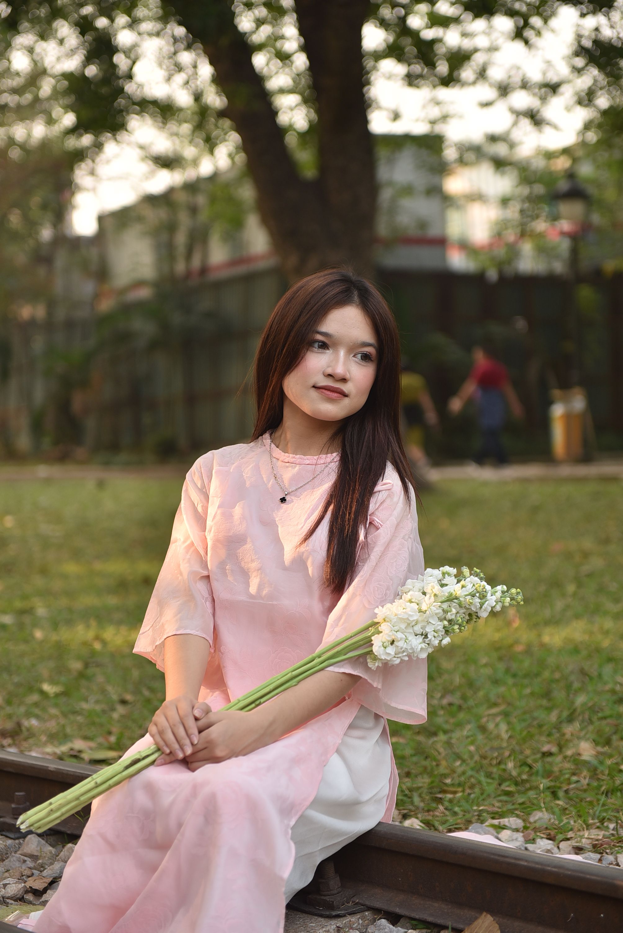 Young Woman in Pink Dress Holding Flowers Outdoors · Free Stock Photo