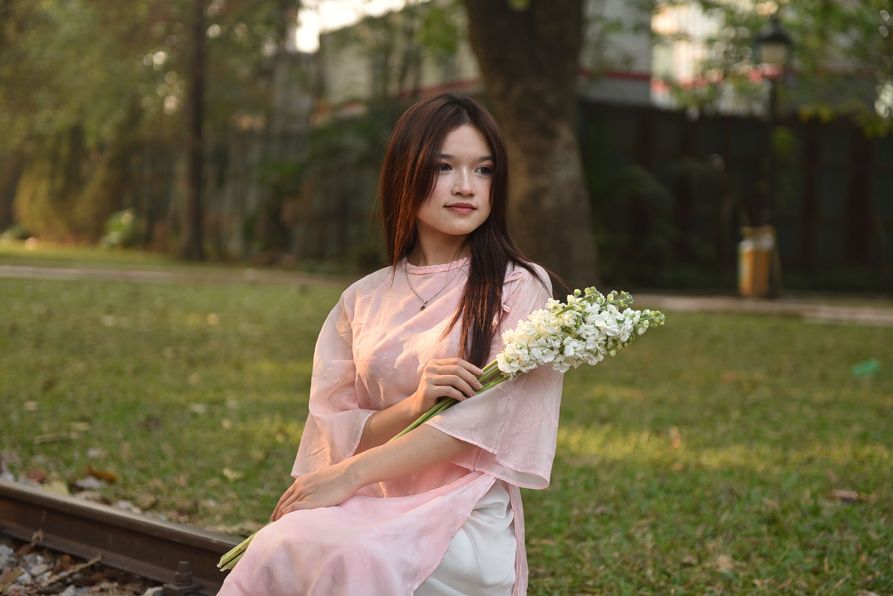 Young Woman in Pink Dress Holding Flowers Outdoors · Free Stock Photo