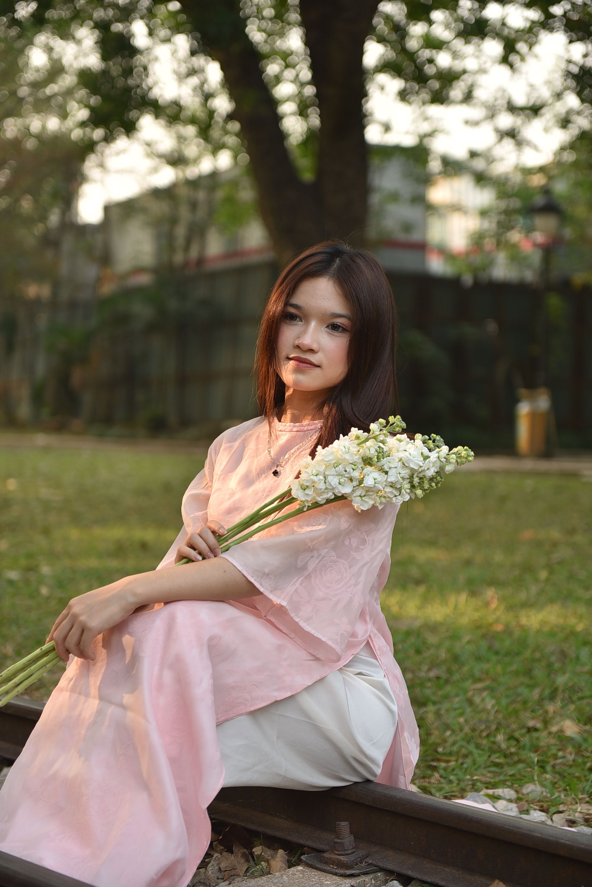 Young Woman in Pink Dress Holding White Flowers Outdoors · Free Stock Photo