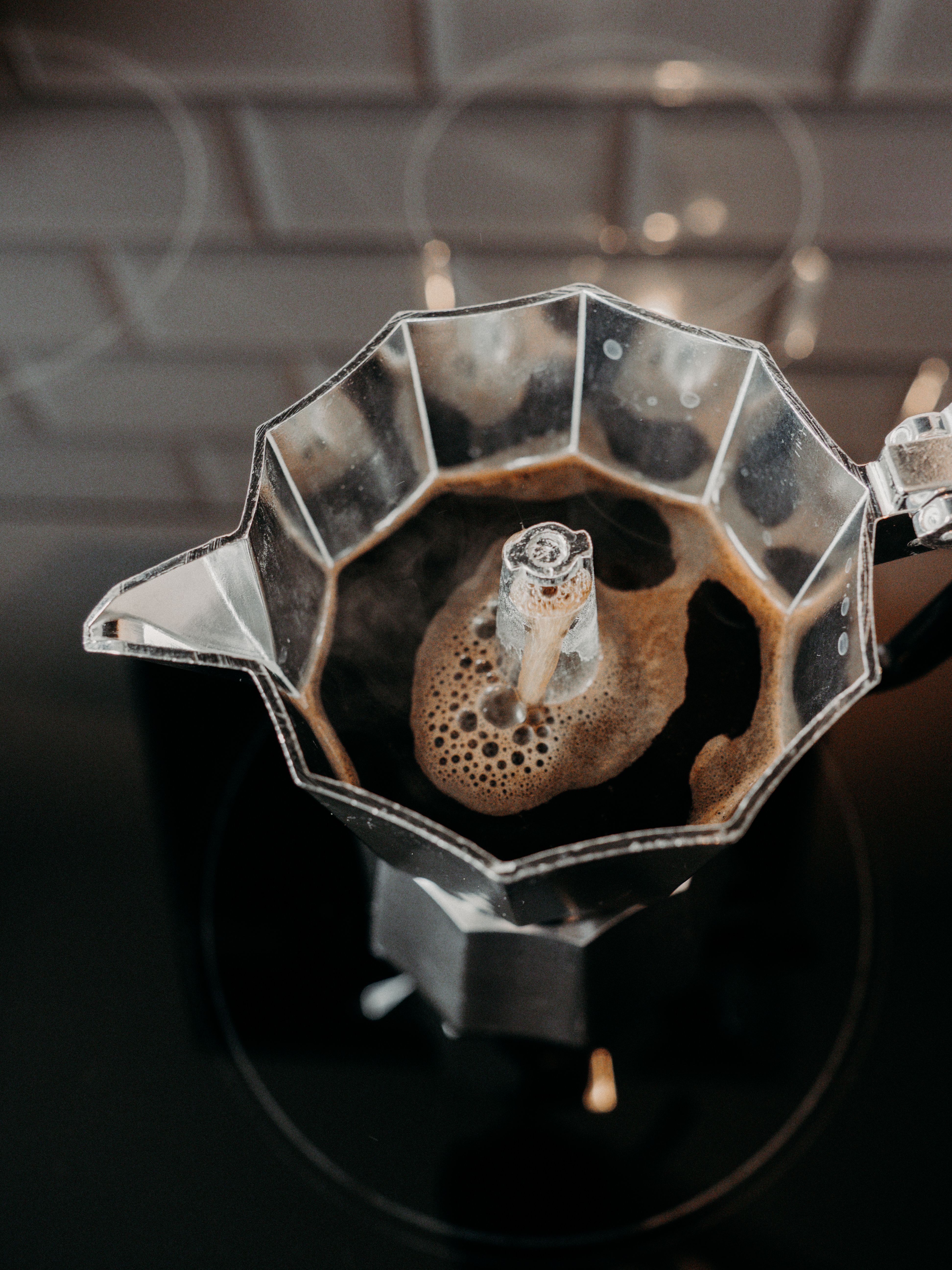 Overhead shot of coffee brewing in a Moka pot on a stovetop. Perfect for coffee lovers.
