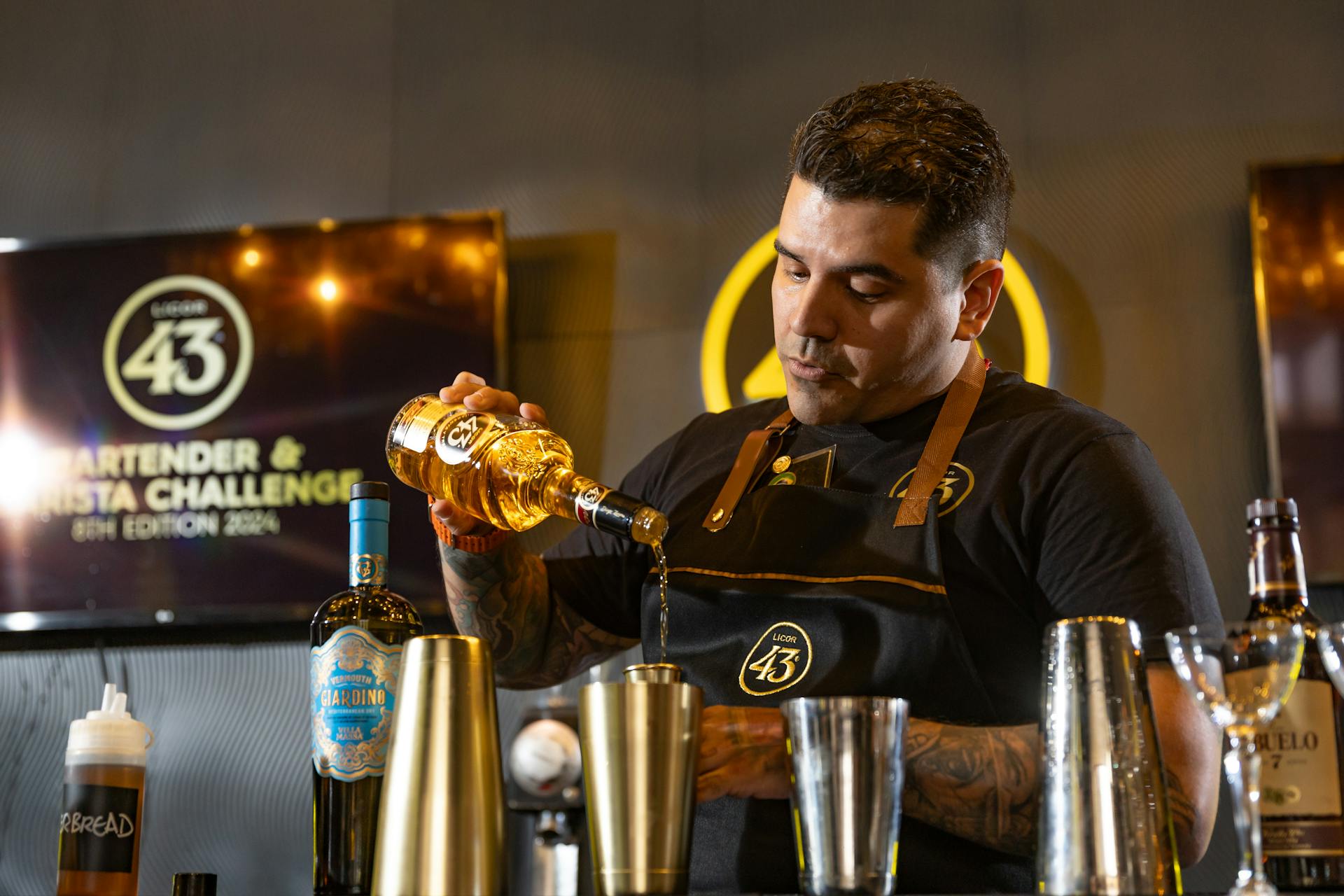 Bartender skillfully pouring liquor at a mixology challenge event.