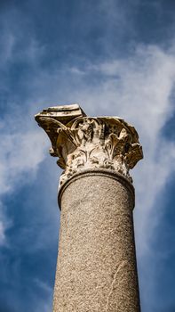 A detailed view of an ancient stone column with ornate carvings against a blue sky.
