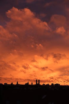 Silhouette of city skyline with dramatic orange sunset sky.