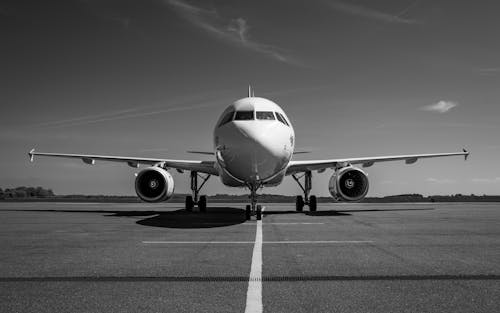 Free Front view of an airplane parked on a runway in a striking black and white photo. Stock Photo