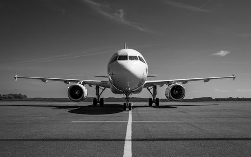 Free Front view of an airplane parked on a runway in a striking black and white photo. Stock Photo