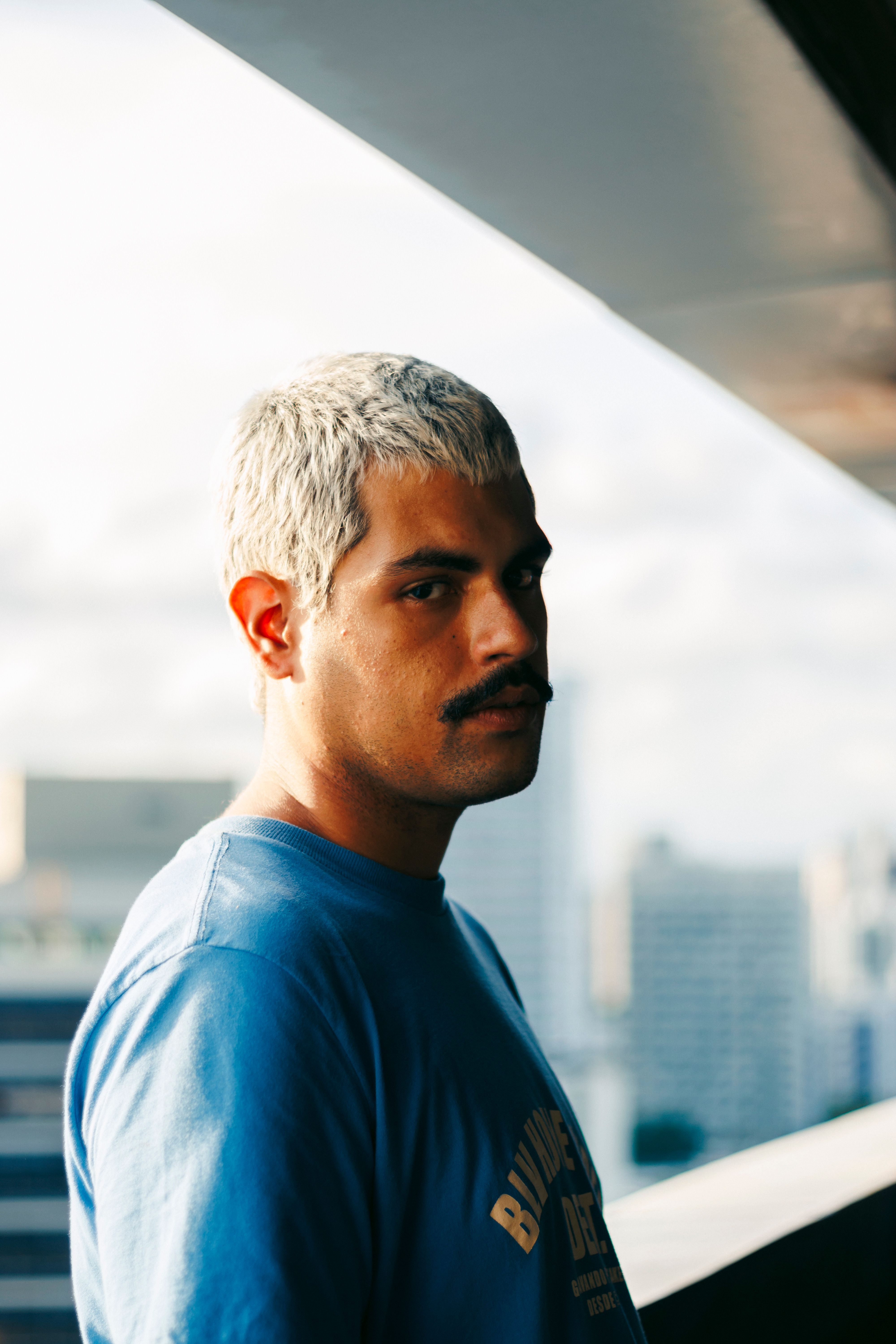 Casual portrait of a man in urban setting with city skyline.