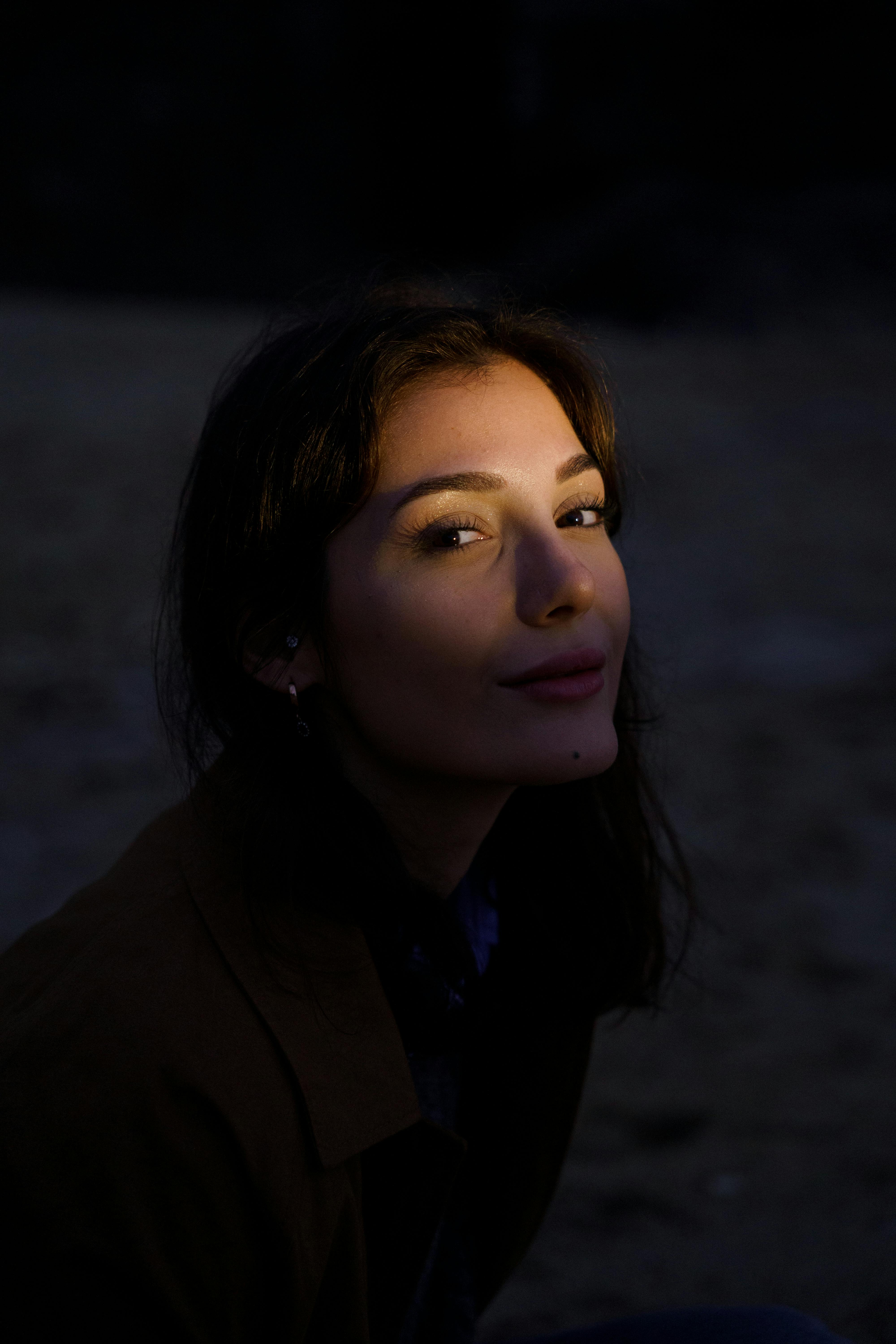 A captivating twilight portrait of a woman with a play of light and shadow creating a mysterious mood.