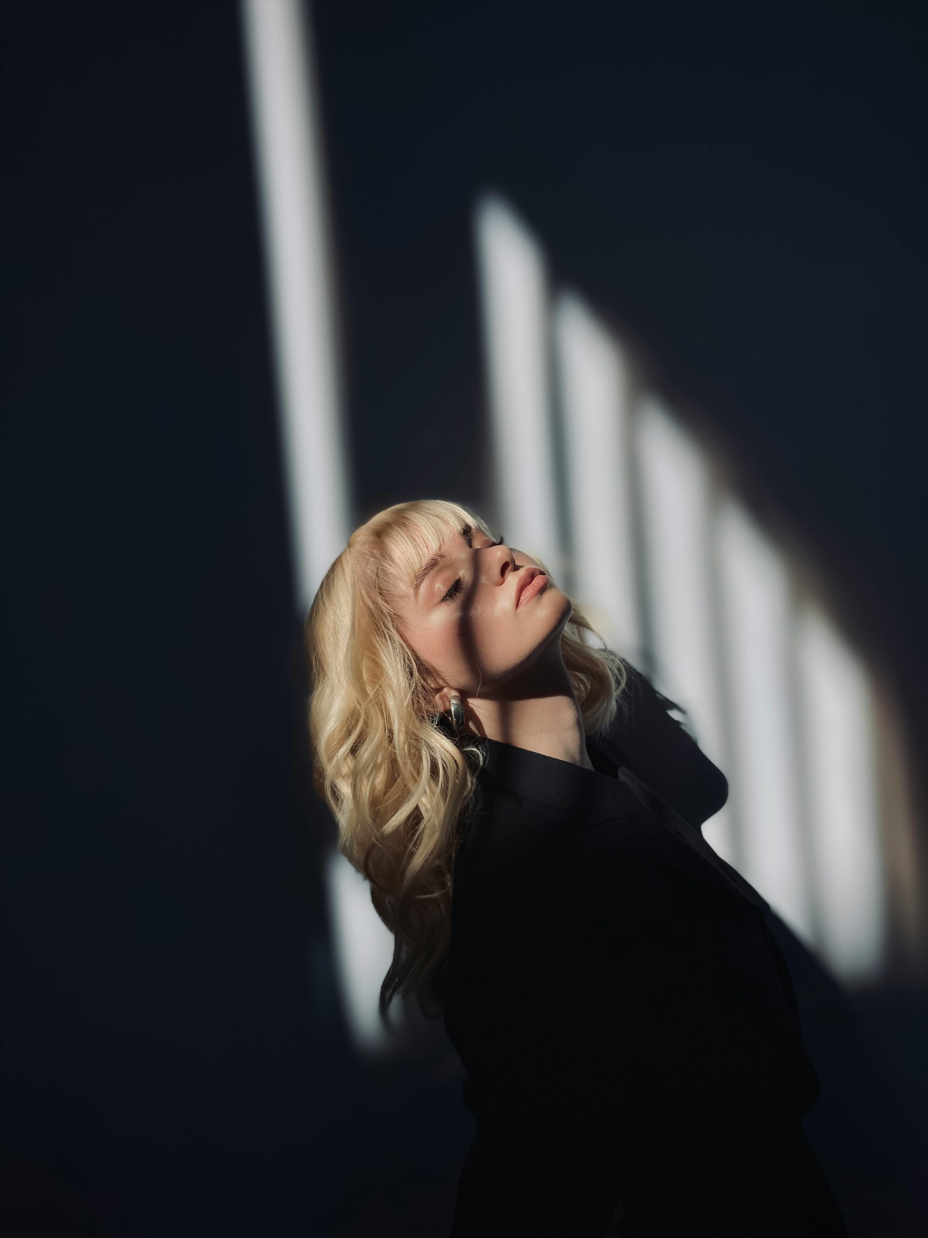 Portrait of a woman with blonde hair in striking shadows and dramatic lighting.