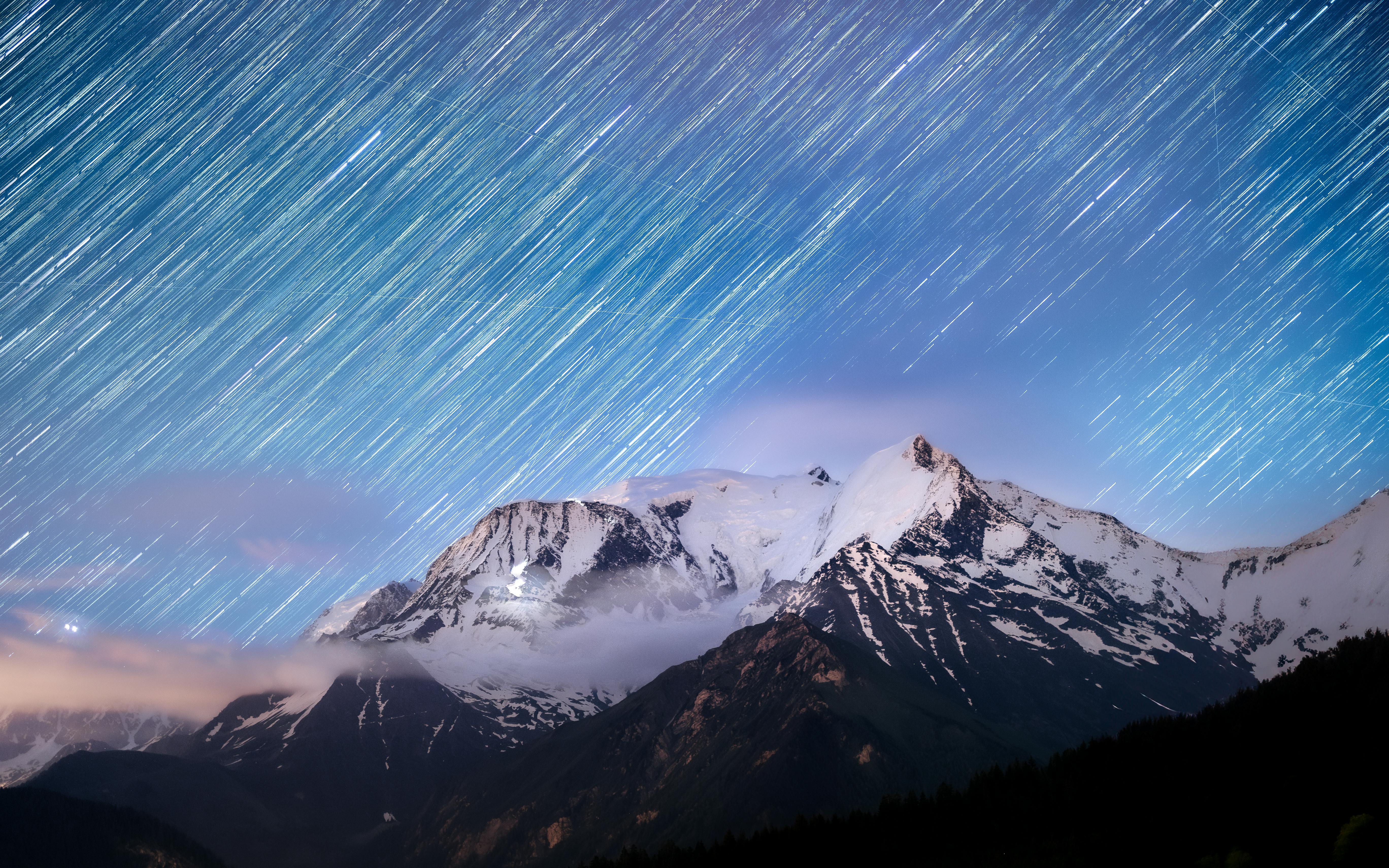 Captivating view of star trails over Mont Blanc with a vibrant sunrise, showcasing natural beauty.
